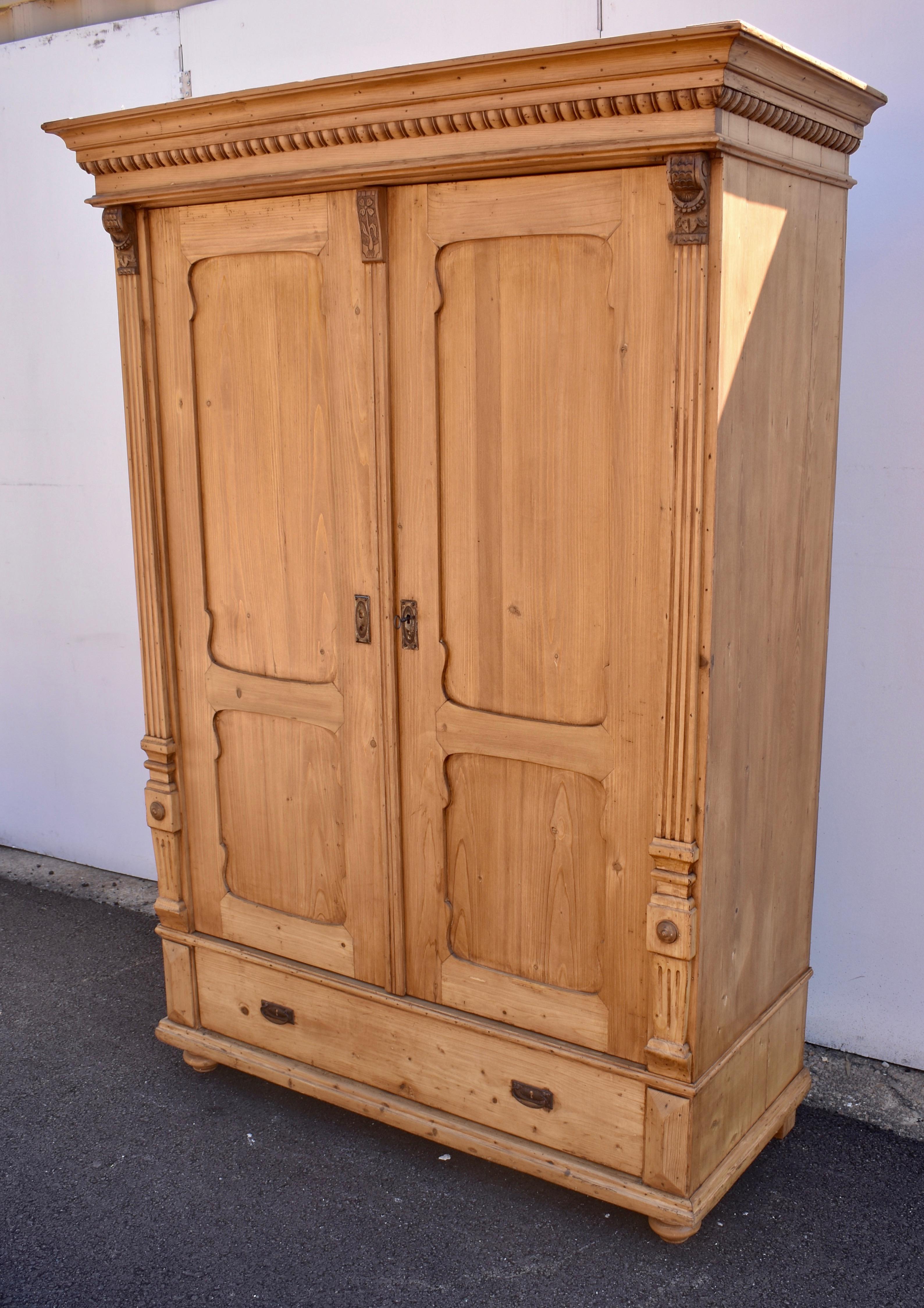 This is a truly extraordinary armoire. The classic reverse-swept crown molding is embellished with bold egg-and-dart type beading beneath, and rests upon two pivot-hinged doors. Each door has two flat panels in scalloped frames, giving the piece a