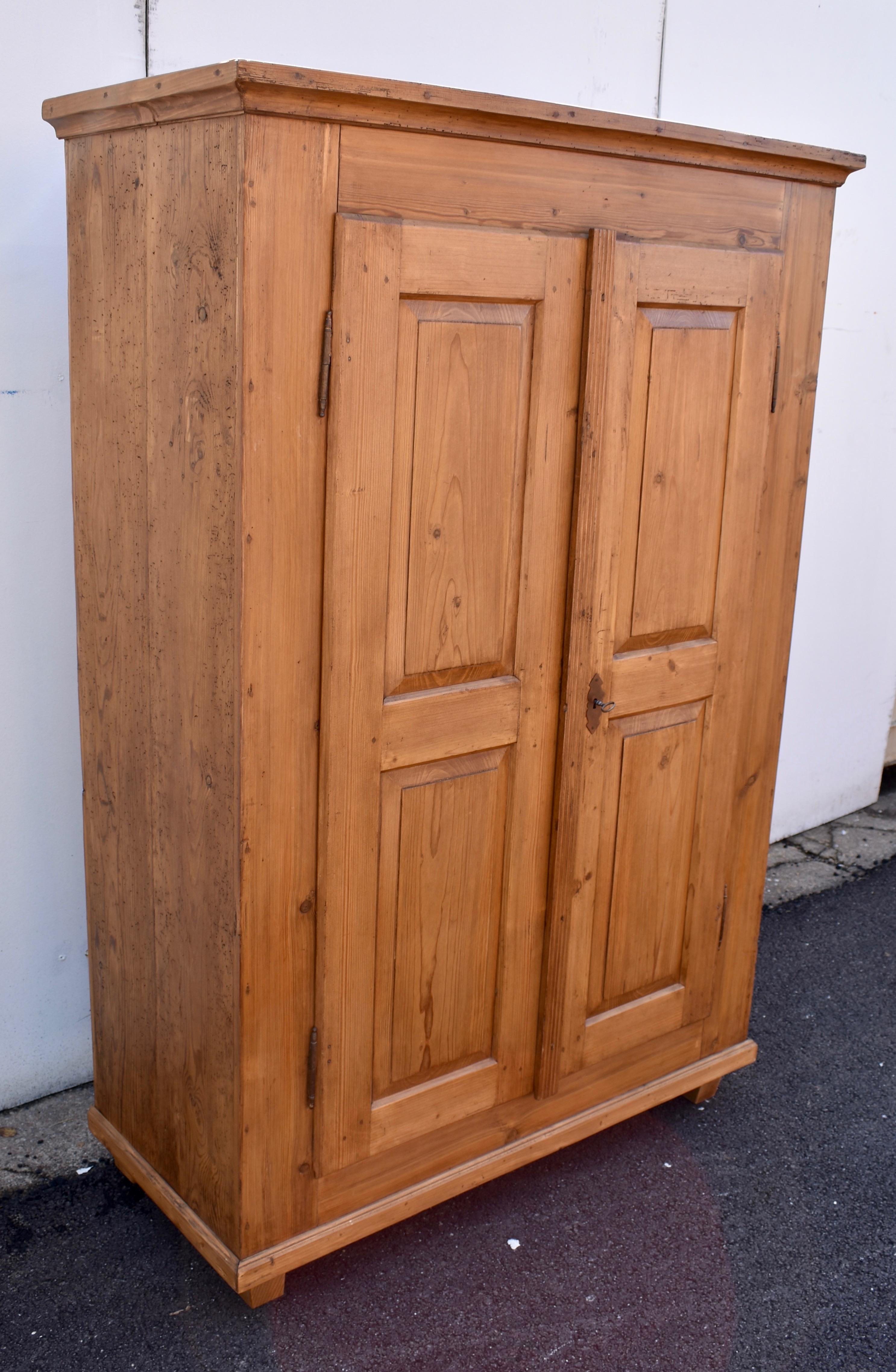This compact little armoire is every bit as sturdy as it looks and the color is every bit as attractive. Beneath a beautifully simple crown is a plain case standing on square tapered feet. The door frames are all pegged and enclose two raised panels