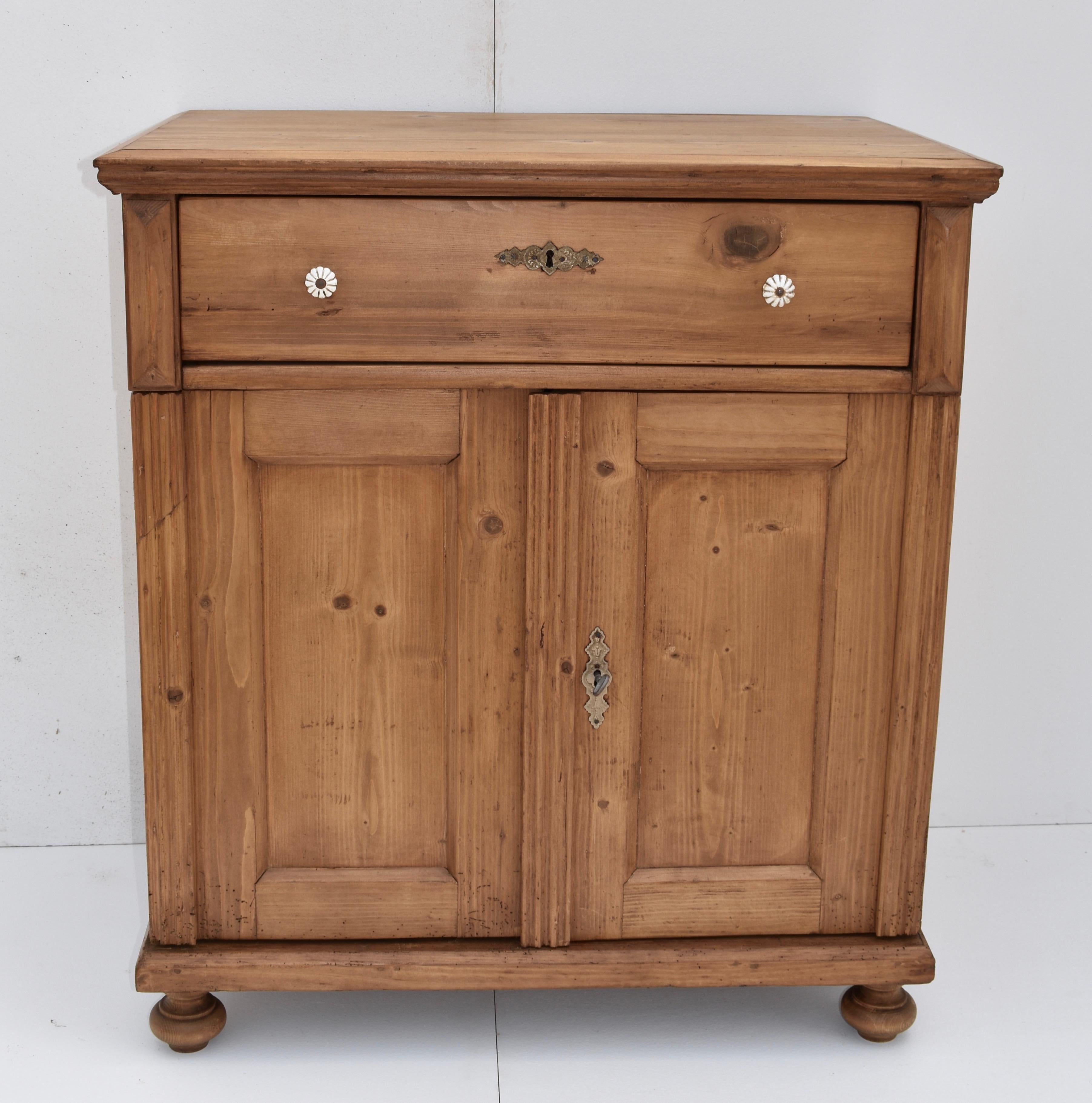 This is a very pretty pine dresser base with a step-down top edge and one long handcut dovetailed drawer above two wide-swinging flat-paneled doors. The front corners are decorated with hand carved fluting.