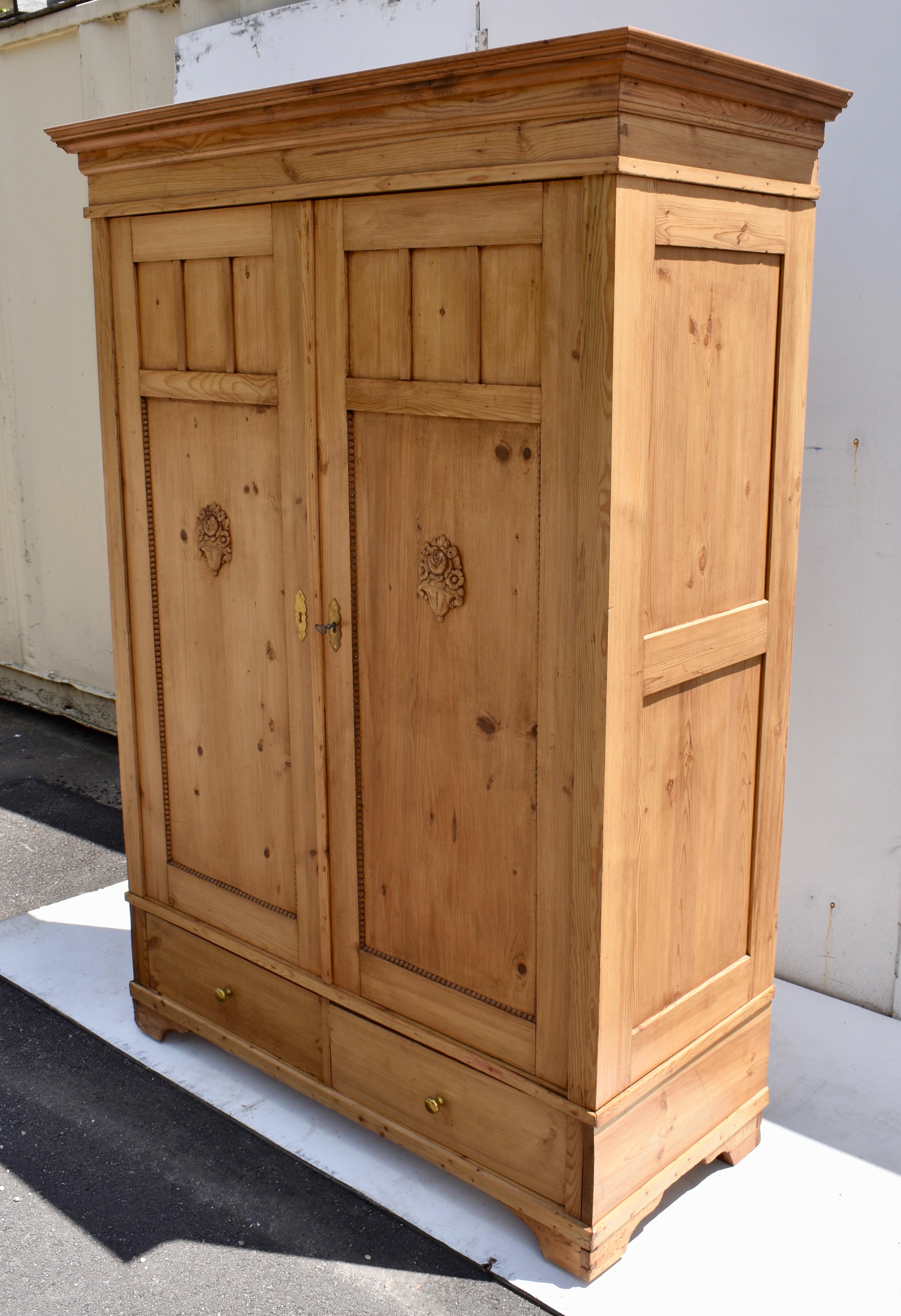 This is an excellent opportunity to purchase a large and handsome knock-down pine armoire at a very reasonable price. Beneath a bold crown molding and a shallow frieze, the two sides are each divided into two equal flat panels. The doors too are