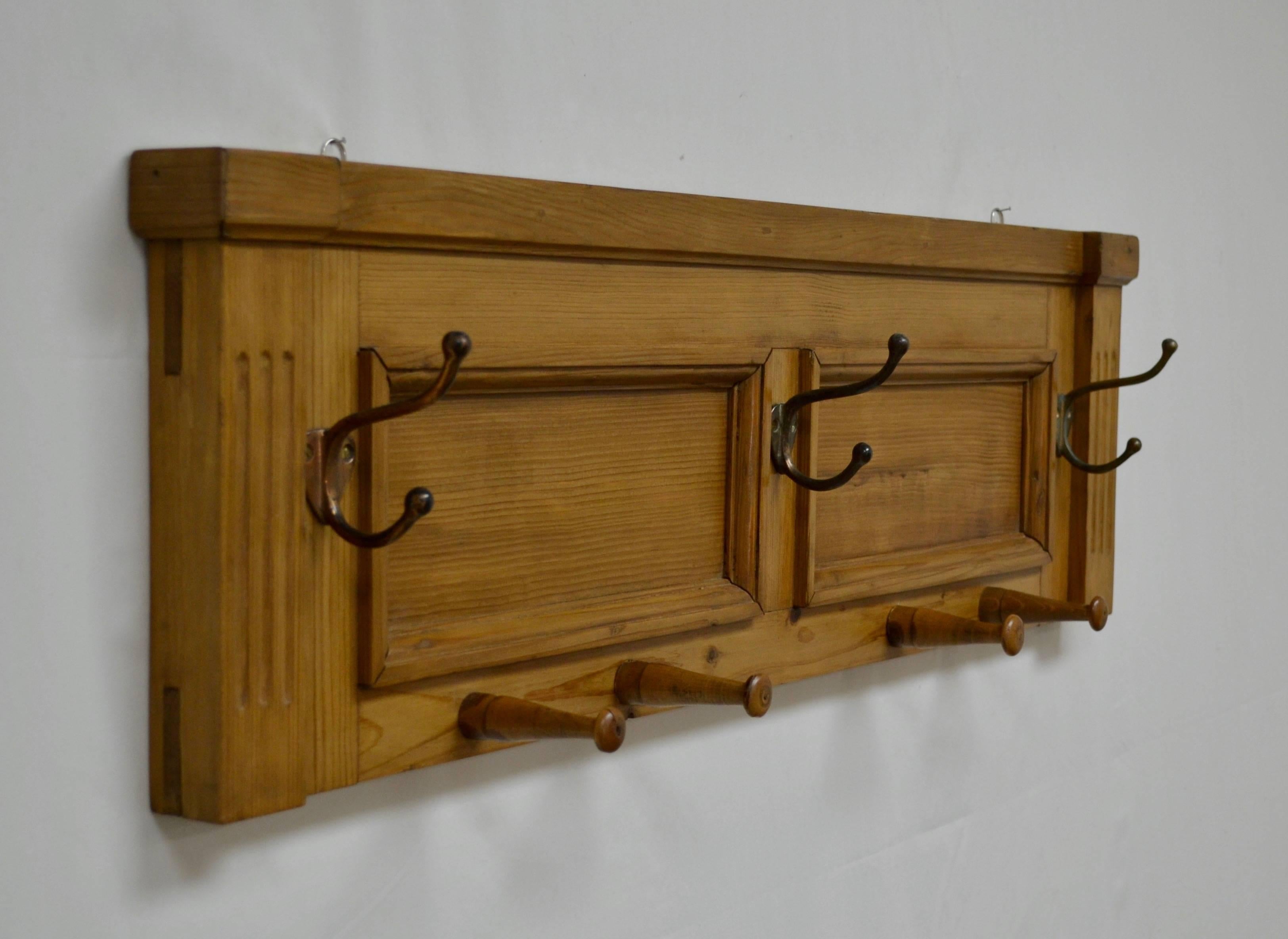 In a creative case of re-purposing, an orphan two panelled backboard from an antique Hungarian pine buffet has been fitted with three vintage metal coat hooks and four antique shaker-style wooden pegs to make this handsome and versatile wall-mounted