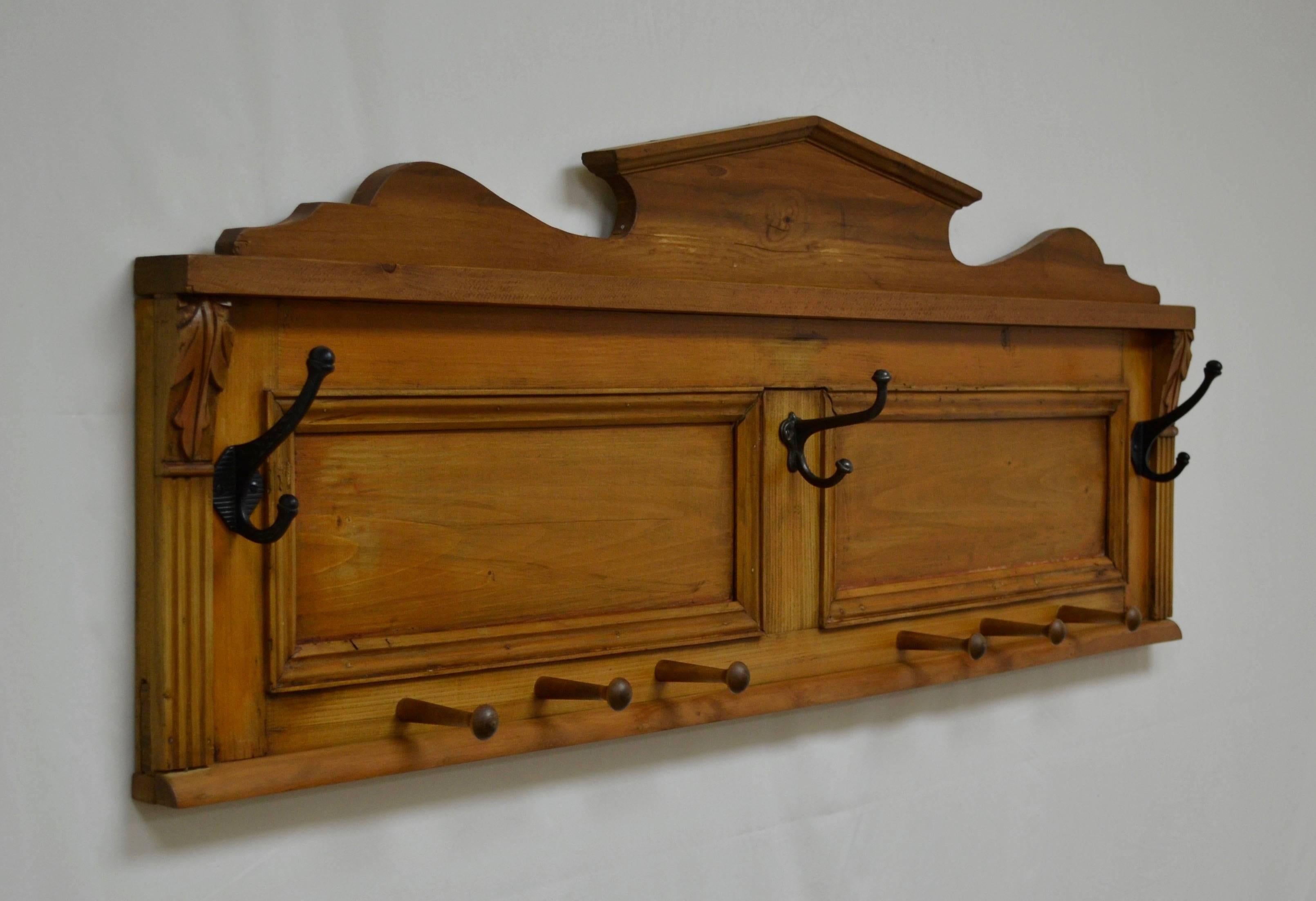 In a creative case of re-purposing, an orphan two paneled backboard from an antique pine buffet, complete with its original fluting and hand-carved acanthus leaf corbels, has been mounted with the abandoned crest from an antique pine armoire. The