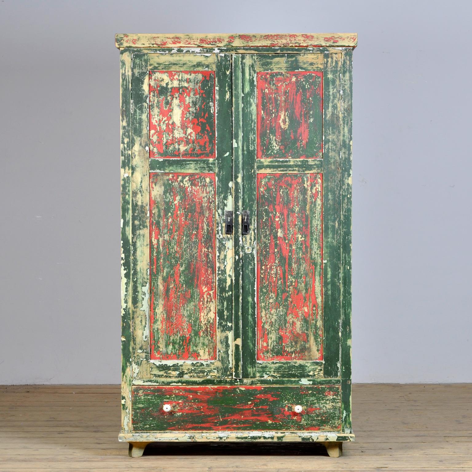 This brocante cabinet comes from Hungary, circa 1920. The cabinet is made of pine wood and has acquired a weathered patina over the years due to the different layers of paint. The cabinet has three shelves. If desired, these can be removed to use