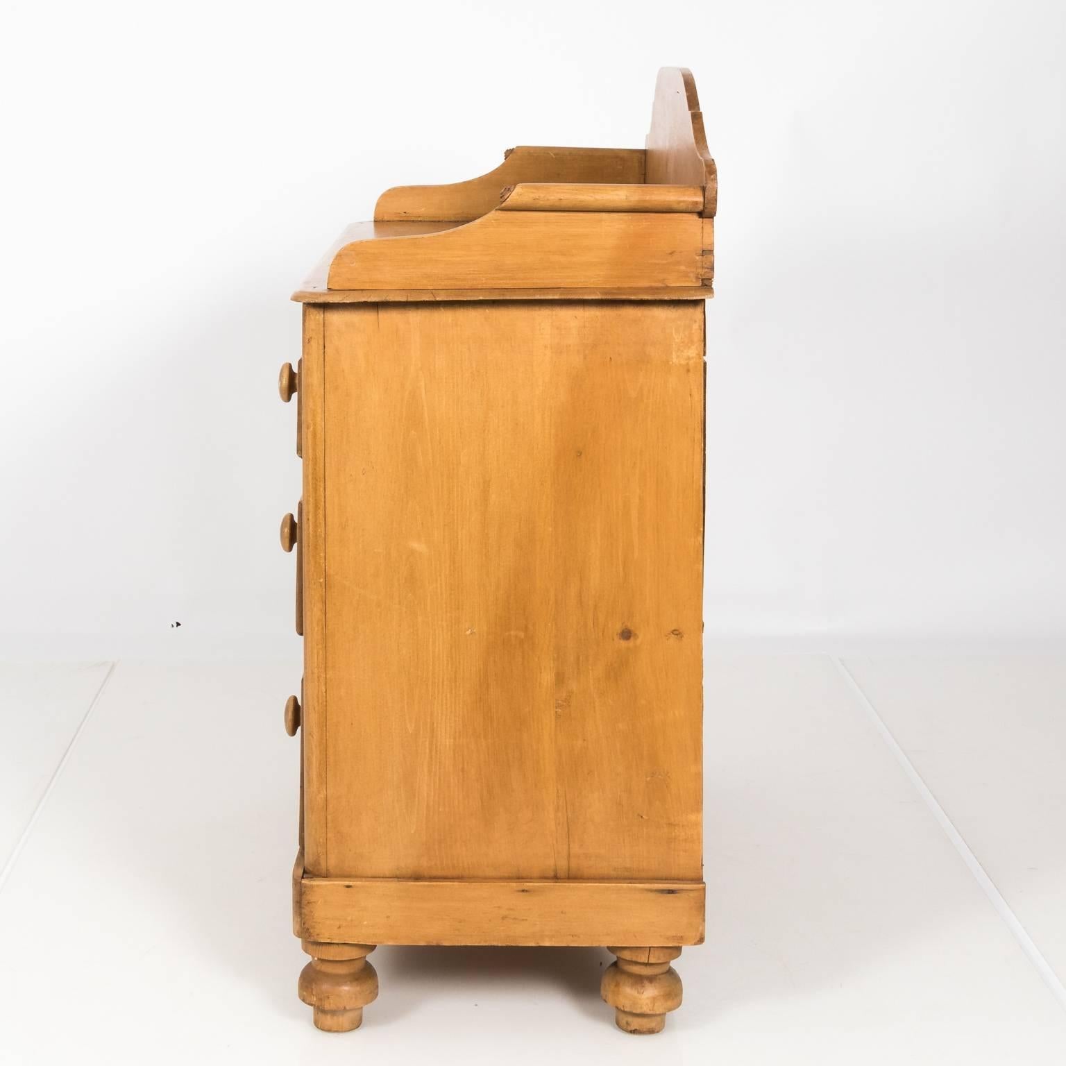 Four-drawer English pine wash stand with a curved splashboard and turned onion feet, circa 1890.
 