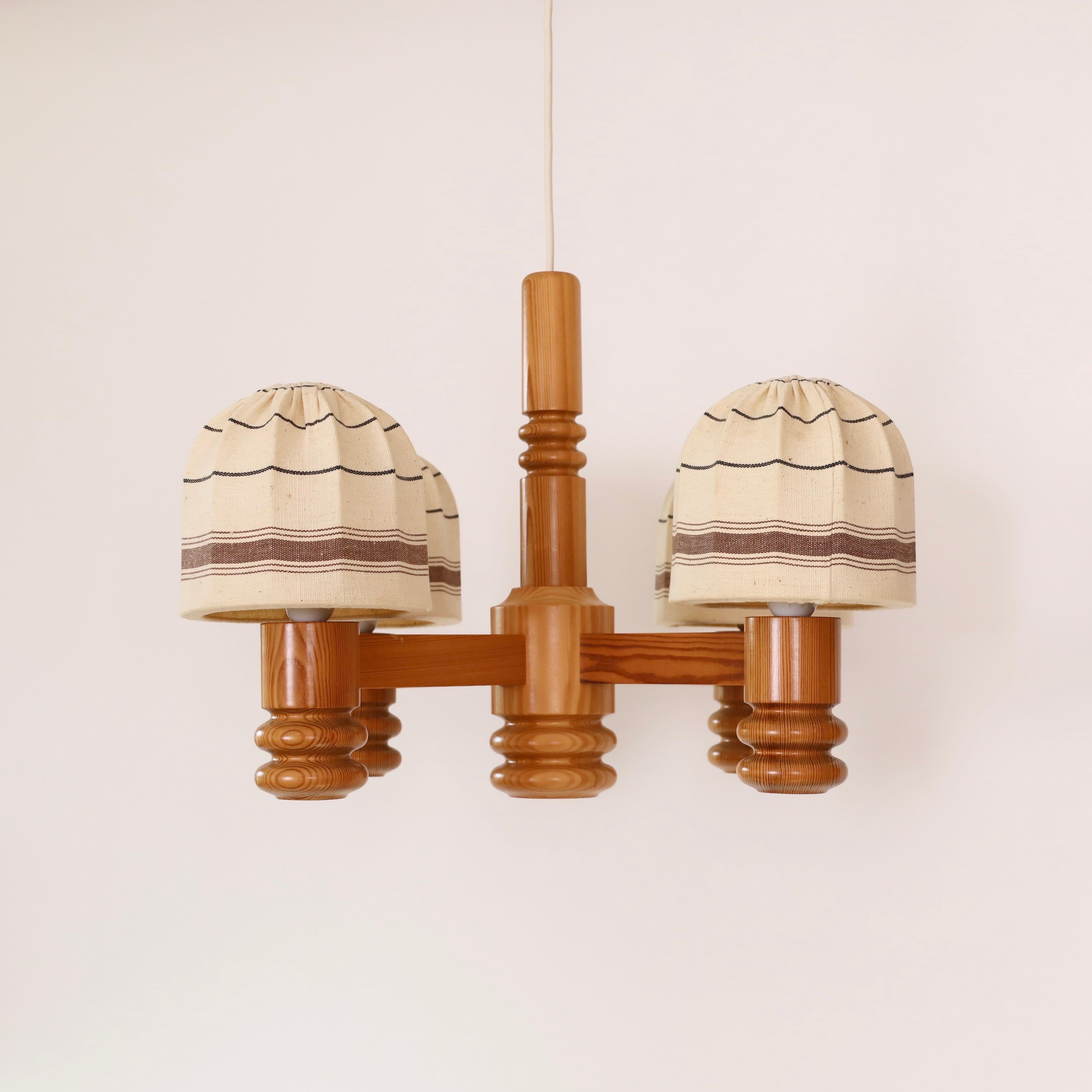 Swedish Modern Pine Wood Chandelier made by Solbackens Svarveri in the 1970s. A Scandinavian touch to a beautiful place.

* A pendant light in pine wood with 4 lights and clip-on fabric shades with beige and brown patterns.
* Manufacturer: