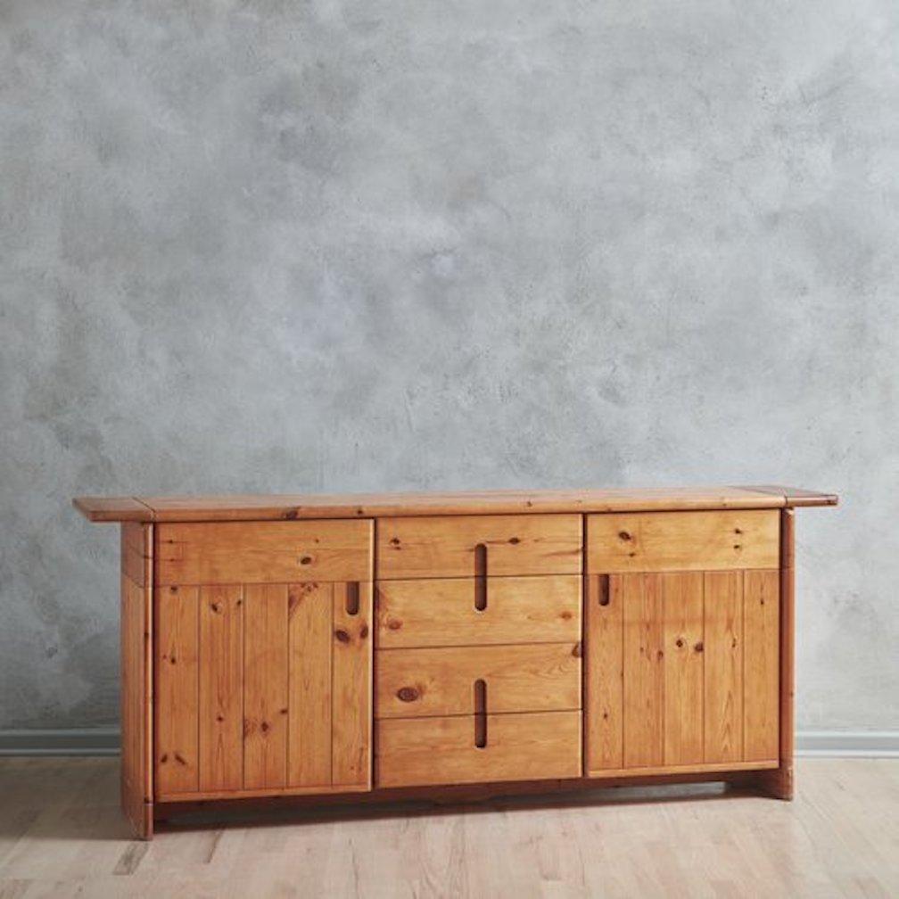 A 1960s brutalist credenza in the style of Italian architect + designer Silvio Coppola. This credenza was constructed with beautifully grained pine wood planks in a delicate honey hue. It has two doors on the left and right sides which open to