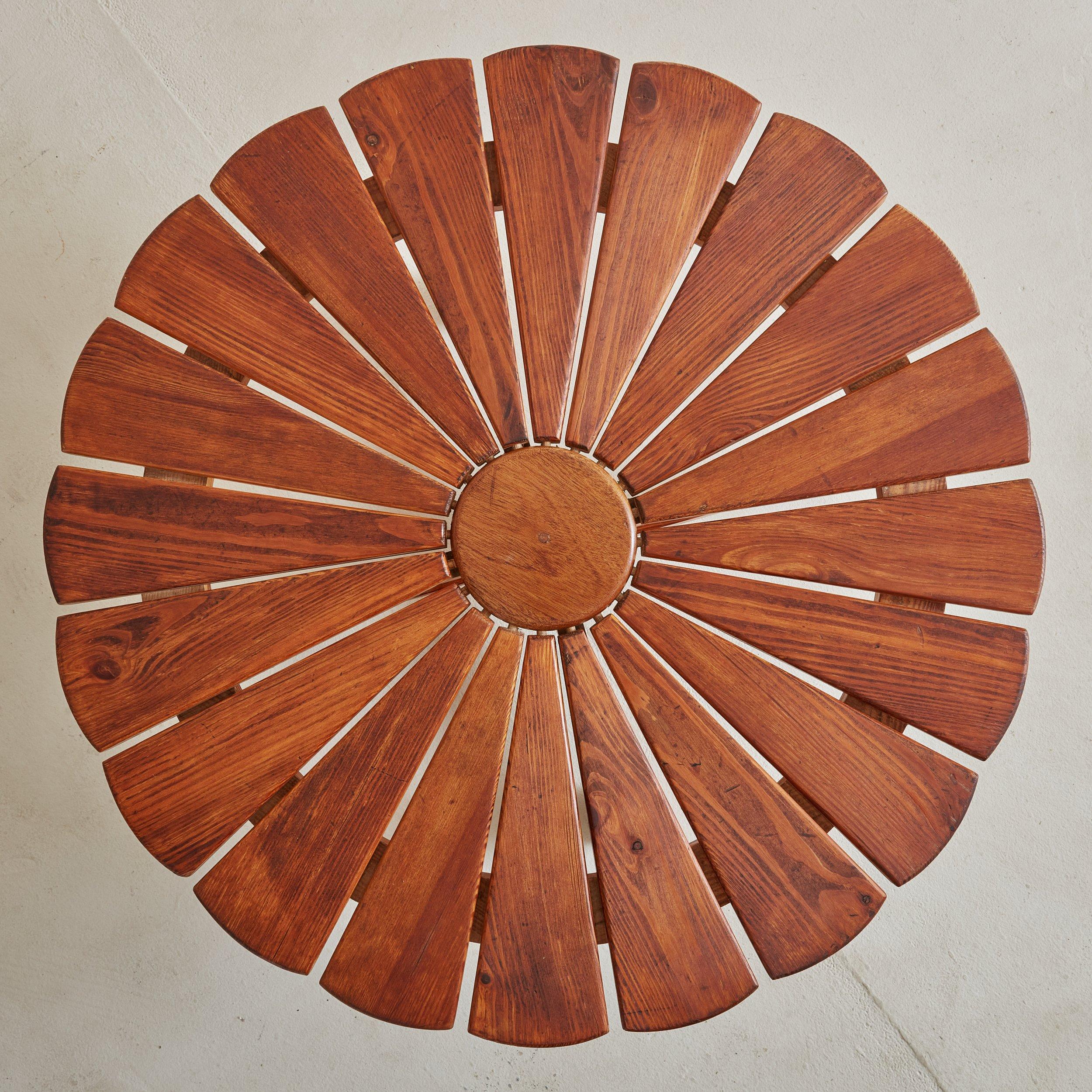 A Mid-Century Modern pine wood flower coffee table from the 1950s. This charming coffee table features a flower top composed of a round center surrounded by symmetric triangular shaped planks. Four tapered angular legs extend from the top and are