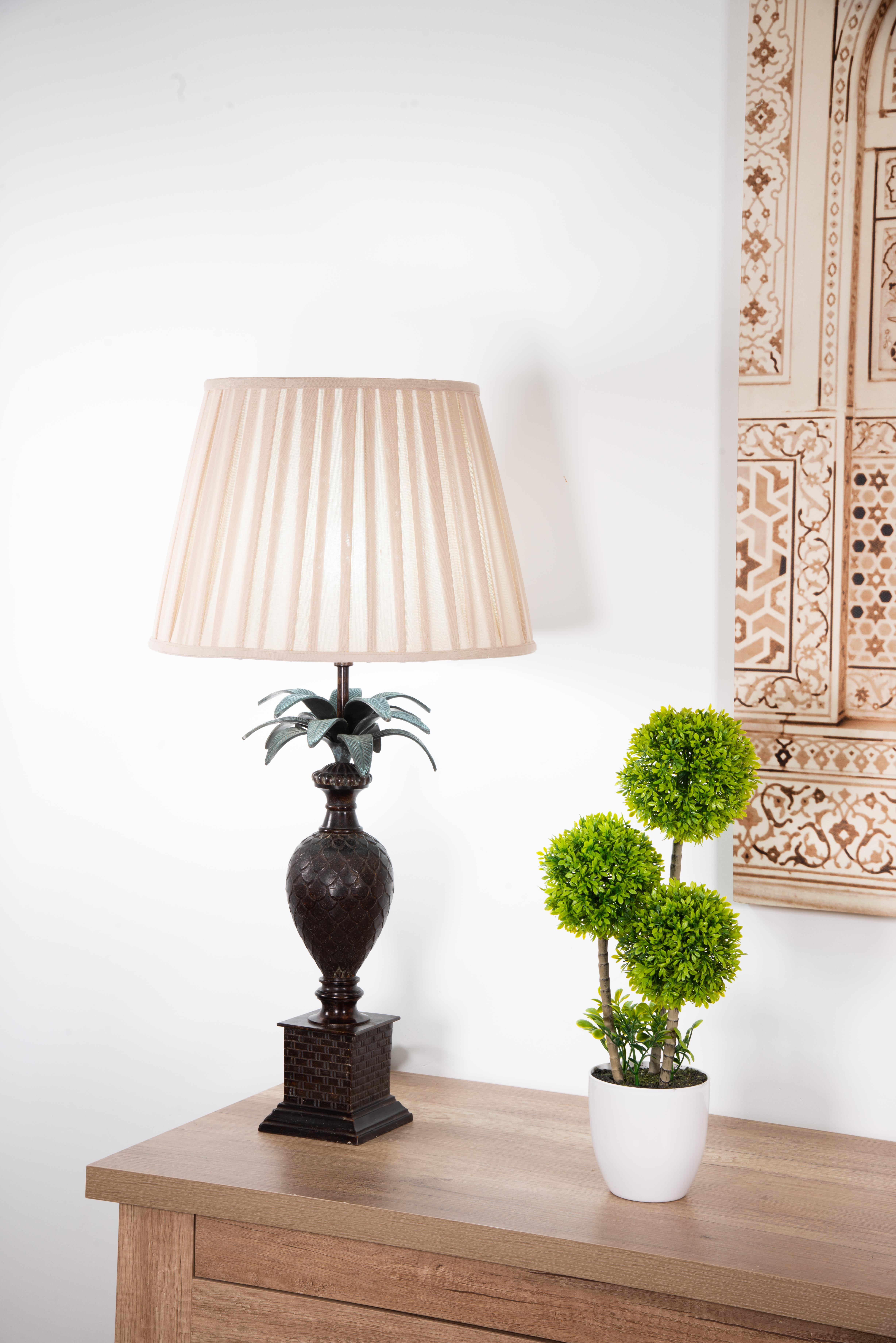 Lámpara de sobremesa en forma de piña, bronce policromado.
 Sin pantalla. 
Un pedestal (con ladrillos simulados en sus frentes) eleva y resalta la piña que forma el cuerpo de esta lámpara. Sin embargo, se trata de un pequeño jarrón con decoración de