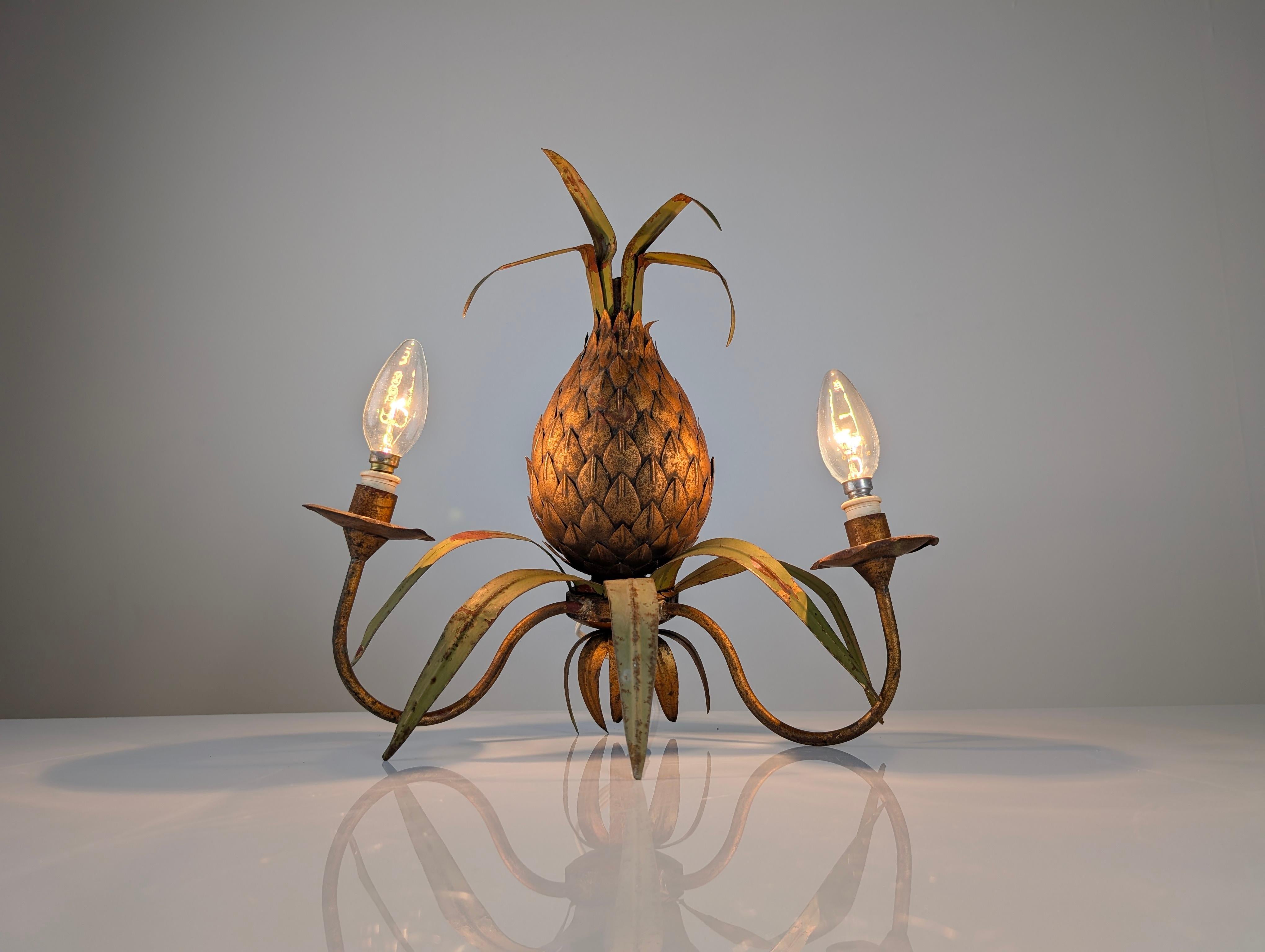 This wall sconce, which evokes the glamour of the 1970s, captures the essence of the Maison Jansen style with its stylized pineapple design. The centerpiece, a golden metal pineapple with a rich and detailed texture, along with its green-toned