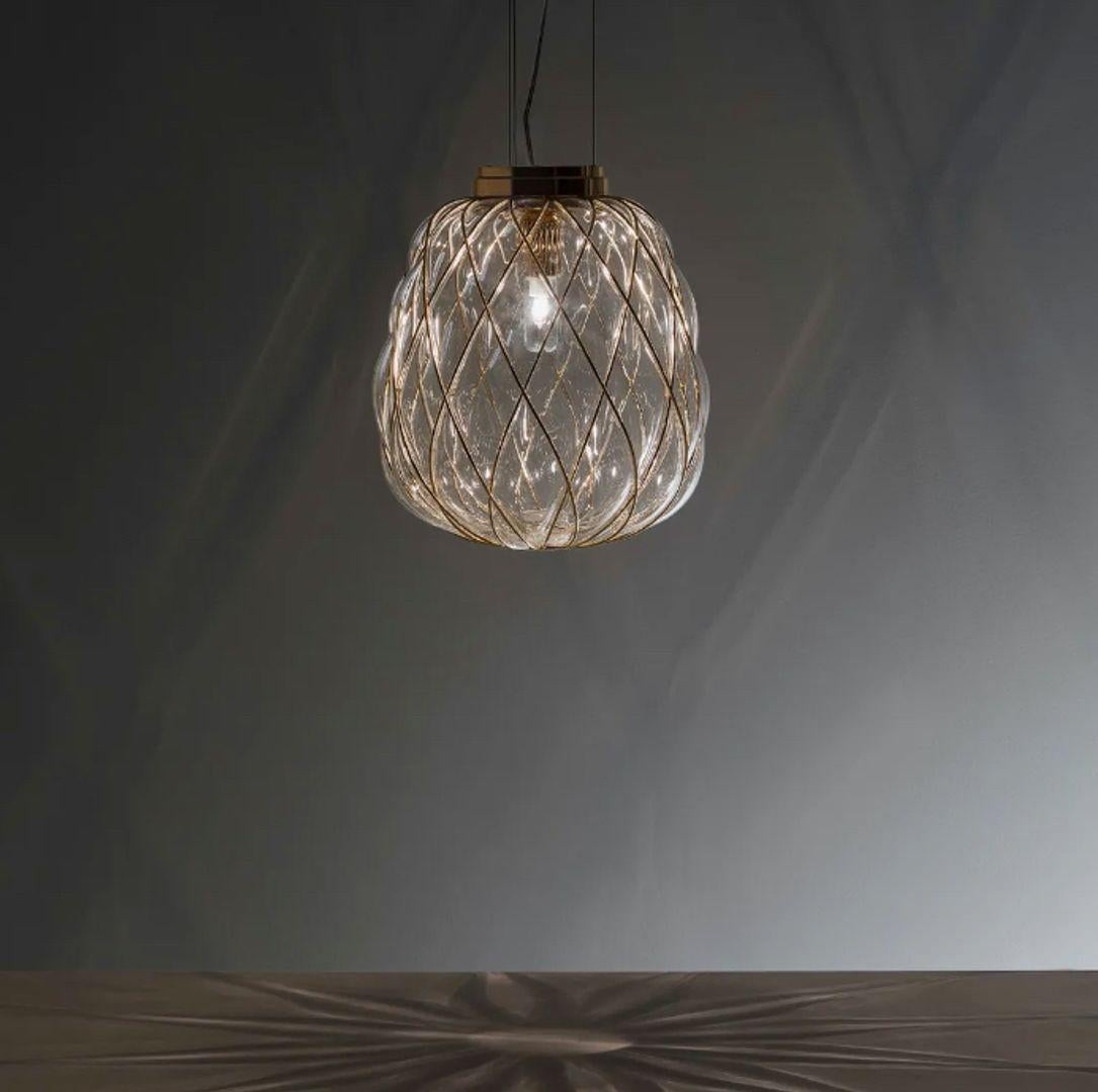Pinecone is a suspension and table lamp. The diffuser is manufactured using the ancient caged blown glass technique: the glass maker blows the molten glass blob into a metal cage, which only partly contains the blob's natural expansion. In this way,