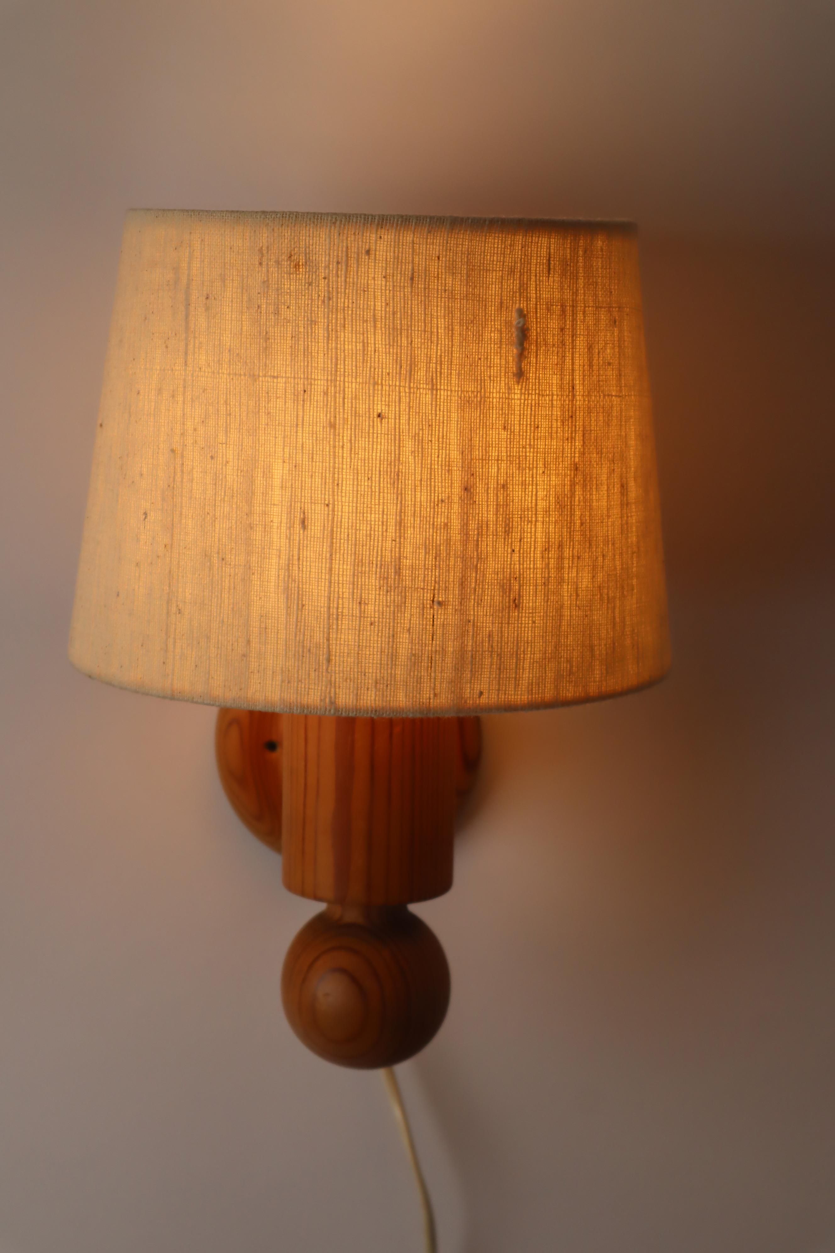 This wall lamp is designed by Uno kristiansson Circa and made by Luxus. The body of this lamp is from pinewood which is very rare and good wood. this is a swidish lamp and it has modern fabric, plastic and pine. The lampshade that sits on top gives