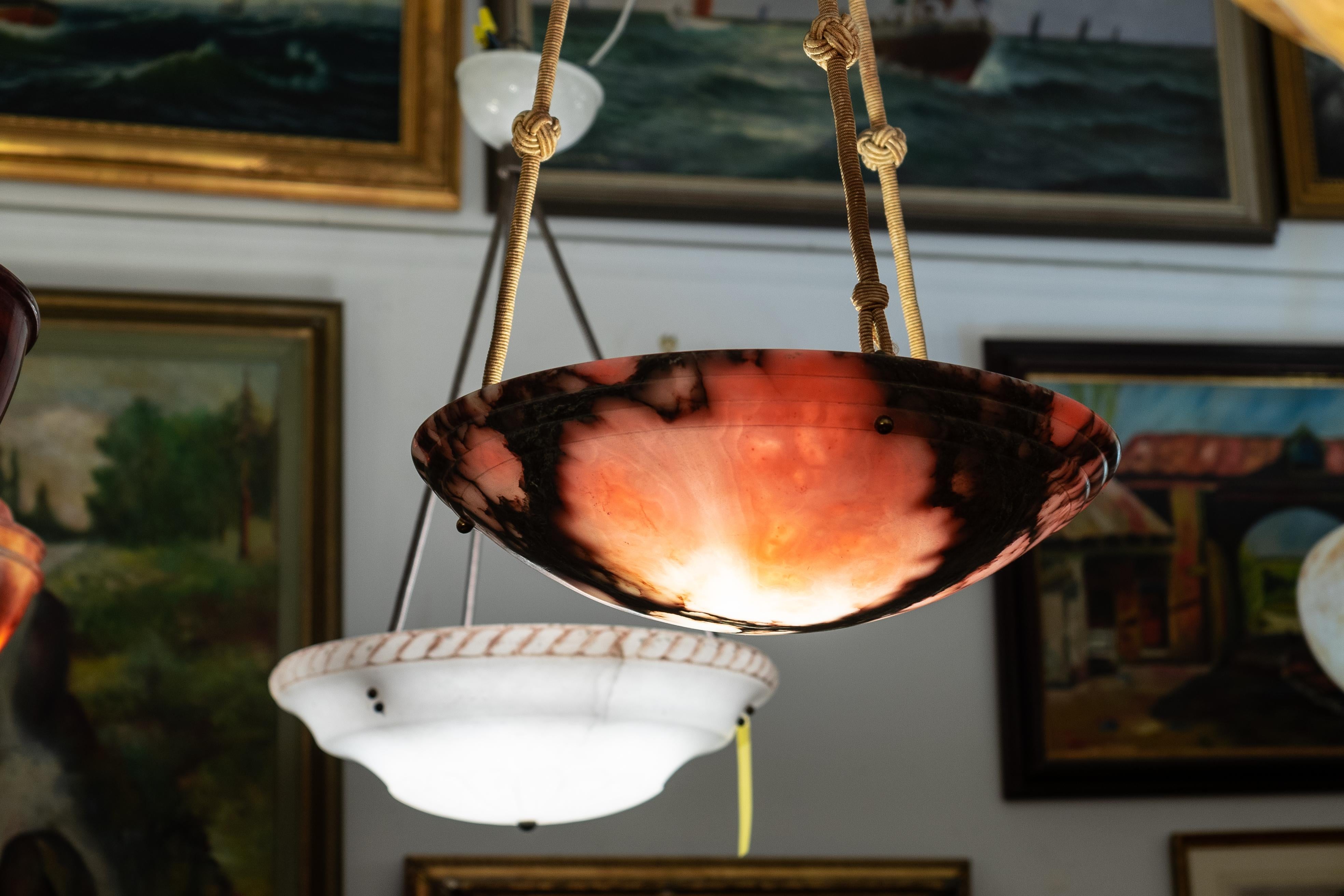 Soft pink tones surround a central charcoal colored vein.  The bowl is in the classical form, and has three upper rings circling the top of the shade.  Cloth ropes and canopy are in good original condition.

This lamp has been rewired for the US