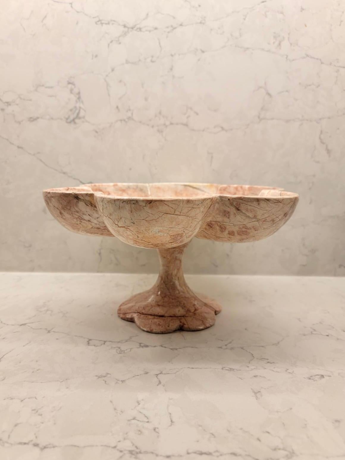 Spectacular pink marble alabaster stone bowl with a pedestal. This stunning bowl stands on a pedestal with scalloped edges. There’s beautiful veining throughout the piece. It’s believed to be hand carved. It can be used as a decorative bowl, it can