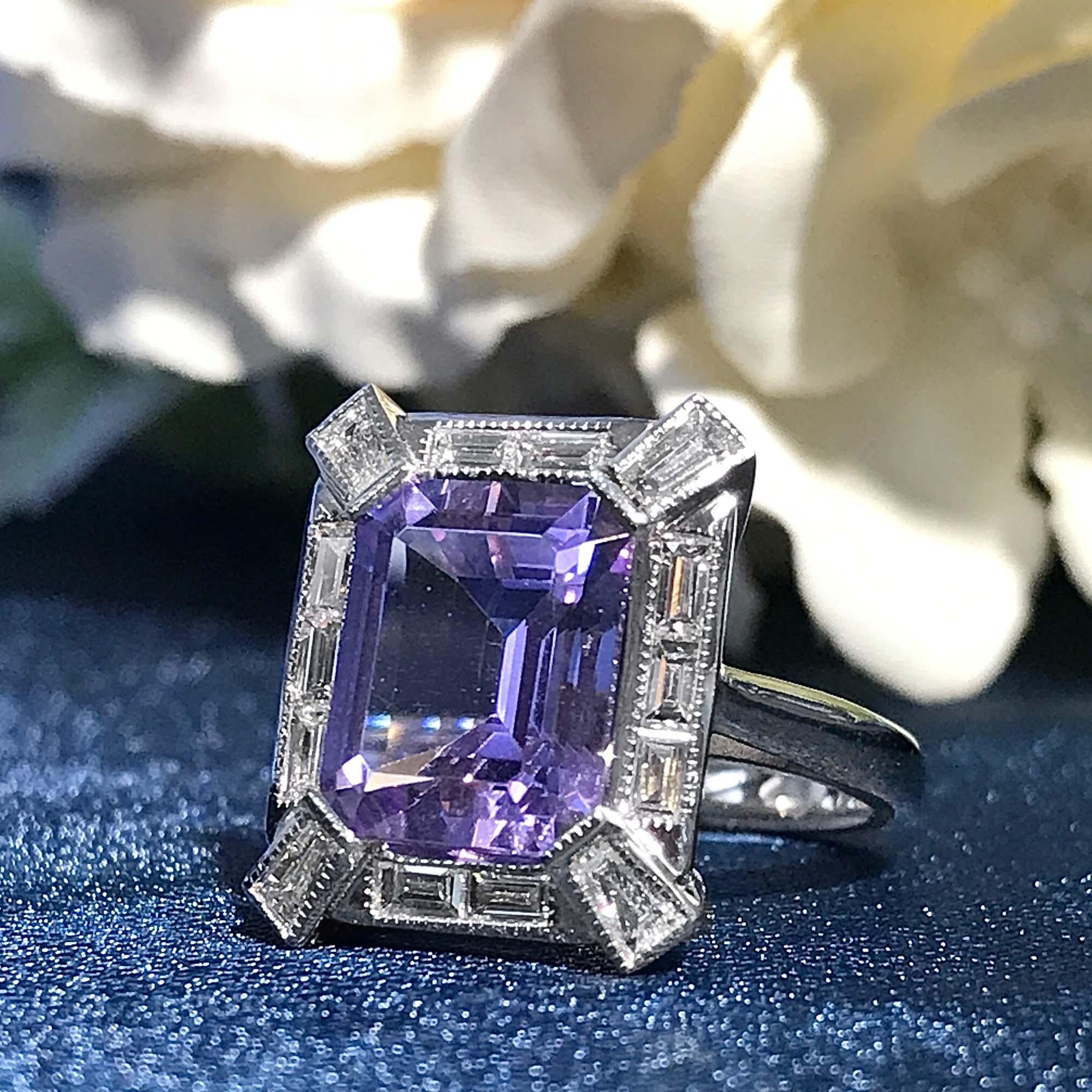 La bague de fiançailles de style Art déco en améthyste rose et diamant baguette présente en son centre une étonnante améthyste rose de forme carrée, qui rayonne d'un charme doux et féminin. Encadré par un halo de diamants étincelants, le design