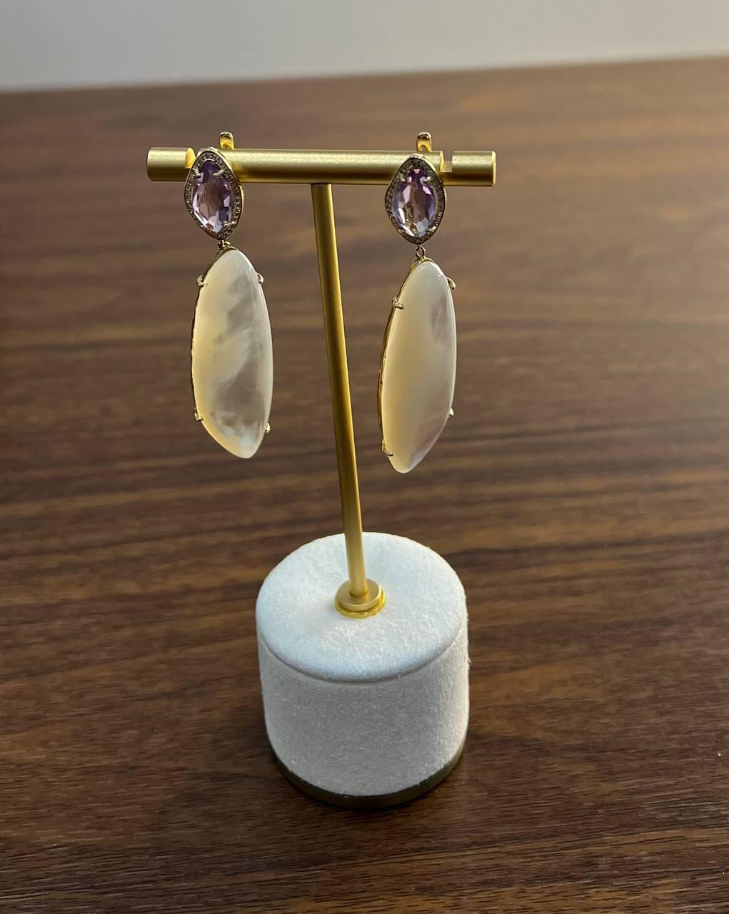 Questi sofisticati orecchini sono realizzati in oro 14k.
Ogni orecchino presenta una pietra di ametista con taglio a marquise incastonata in una montatura sicura. Un'aureola di diamanti.
In basso è sospesa una madreperla ovale, liscia e allungata,