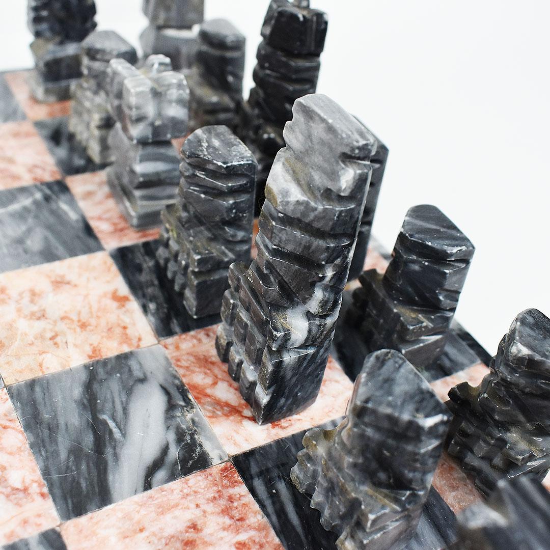 Complete set of carved marble chess board and matching pieces. The squares on the board are created from a rose pink marble, and black marble. Both have wonderful veining. Surrounding the game board is a black marble frame. 

The pieces come as a