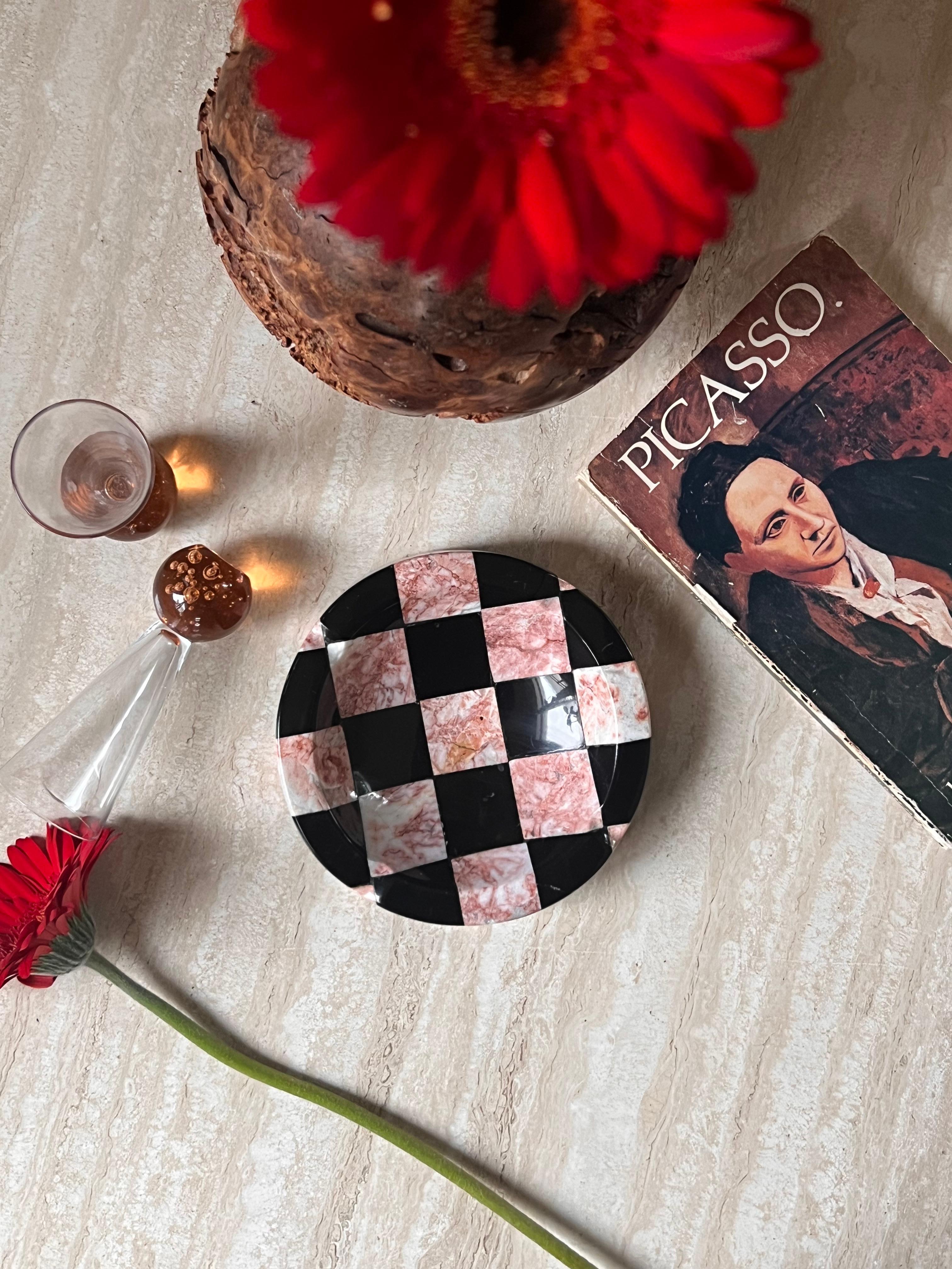 A checkered marble ashtray in tones of peony pink and licorice black, made in Italy circa 1960s. Rivulets are stunted along the edge. A statement ashtray or vide-poche to enliven any room.