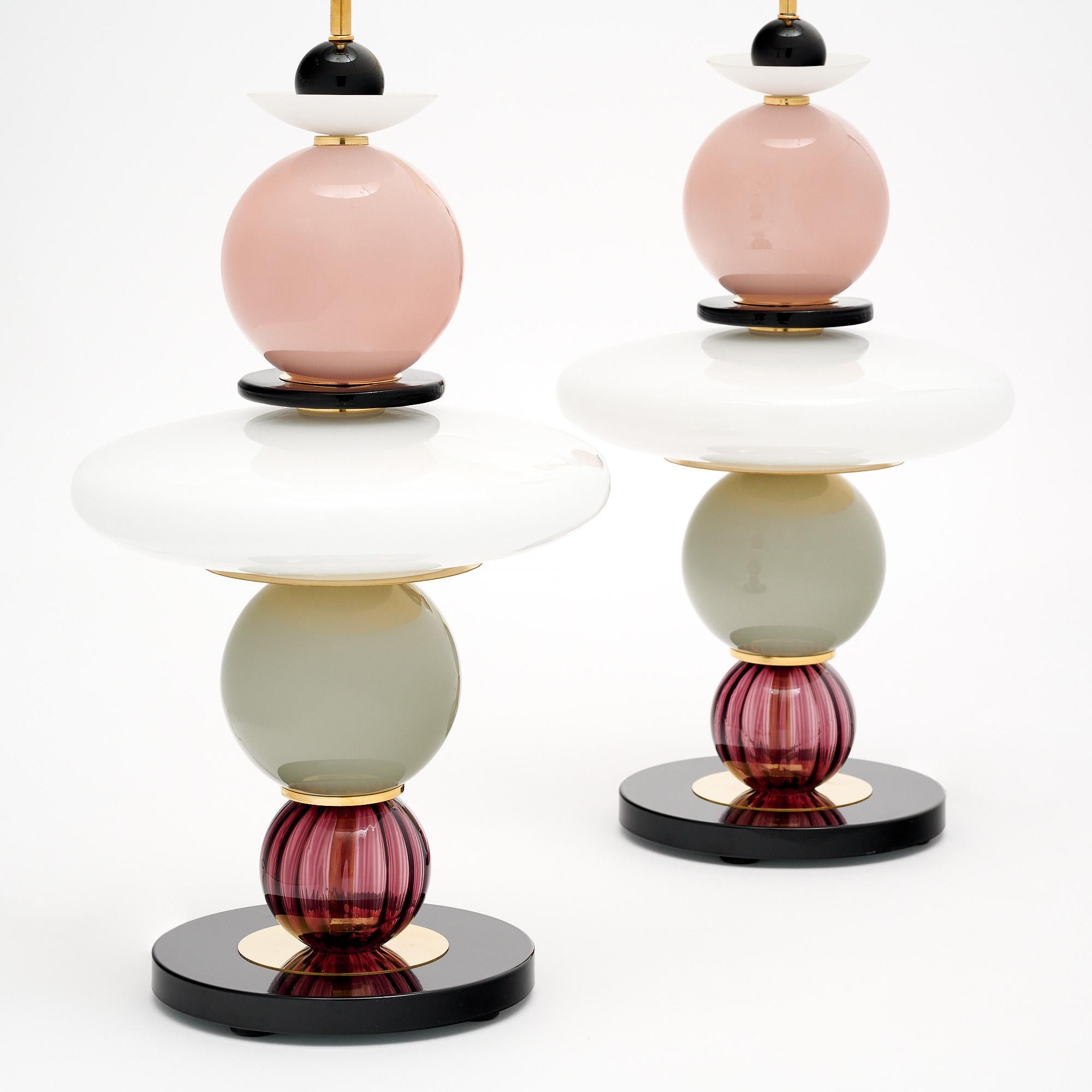 Pair of table lamps made of hand-blown glass elements from Murano, Italy outside of Venice. Each lamp features unique glass components in pink, black and white tones on a brass structure. We love the geometric forms and bold tones this pair brings