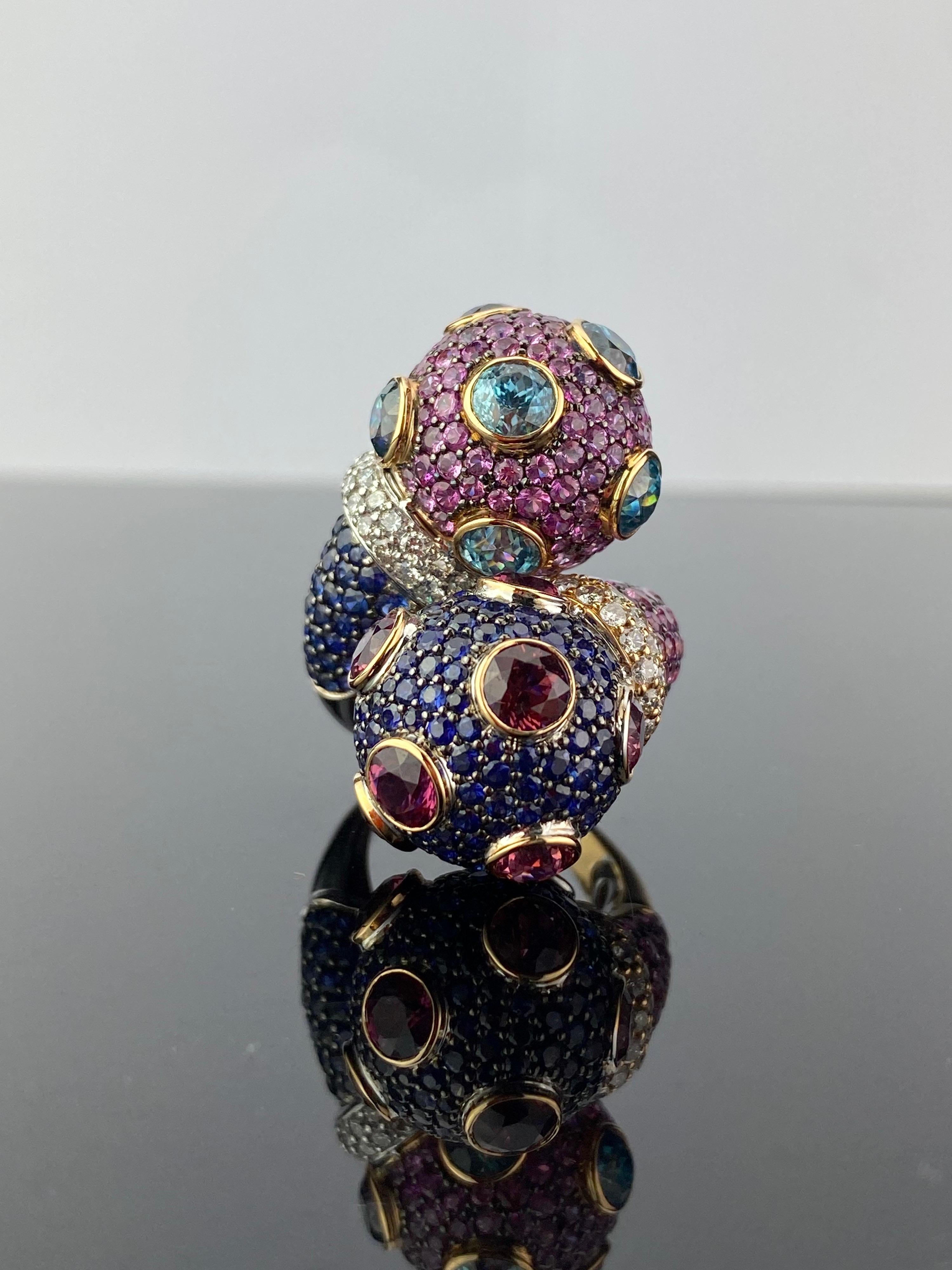 A very unique dome-shaped cocktail ring, with 5.75 carat Blue Sapphire, 5.59 carat Pink Sapphire, 10.92 carats Blue Zircon, 4.8 carat Pink Tourmaline and 1.33 carat White Diamonds all set in 23.10 grams of solid 18K White and Yellow Gold. All