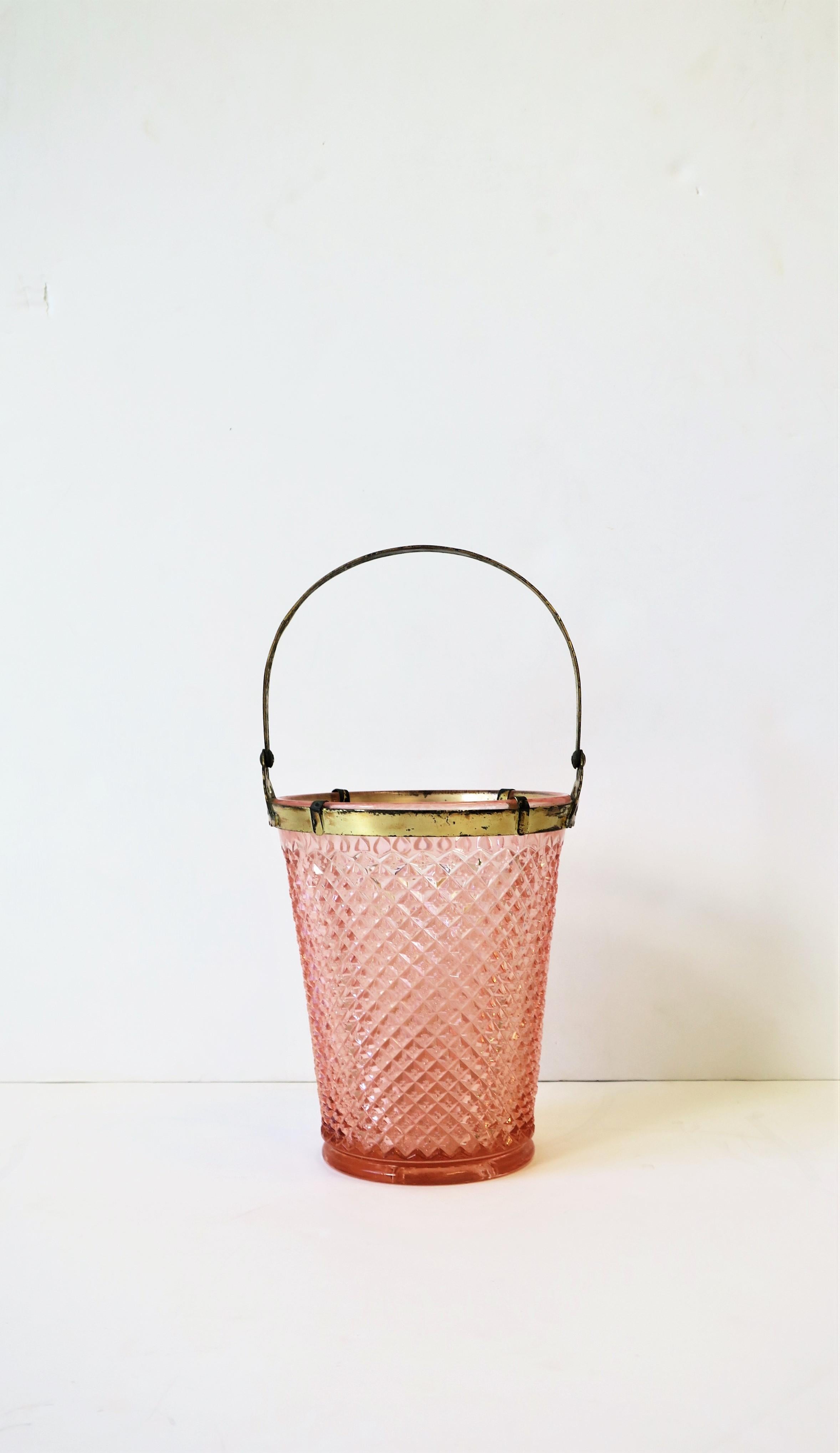 A beautiful early 20th century pink glass ice bucket with a gold-tone metal handle. Glass exterior has a perforated diamond-like design and a gold-tone metal detailed handle; handle is adjustable as show in images. A great addition to any bar, bar