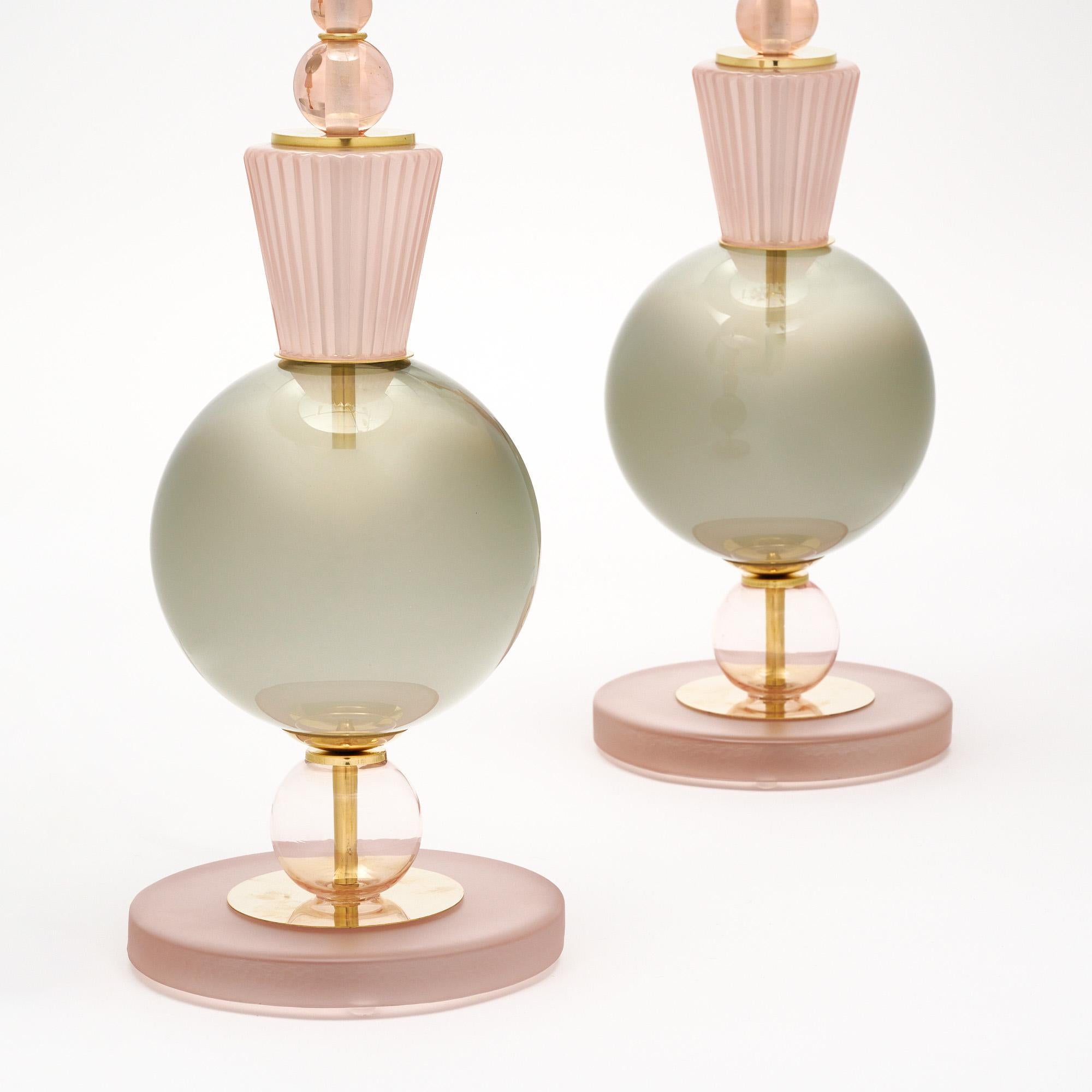 Coppia di lampade da tavolo realizzate con elementi in vetro soffiato a mano provenienti da Murano, in Italia, alle porte di Venezia. Ogni lampada è caratterizzata da componenti in vetro unici nei toni del grigio e del rosa su una struttura in
