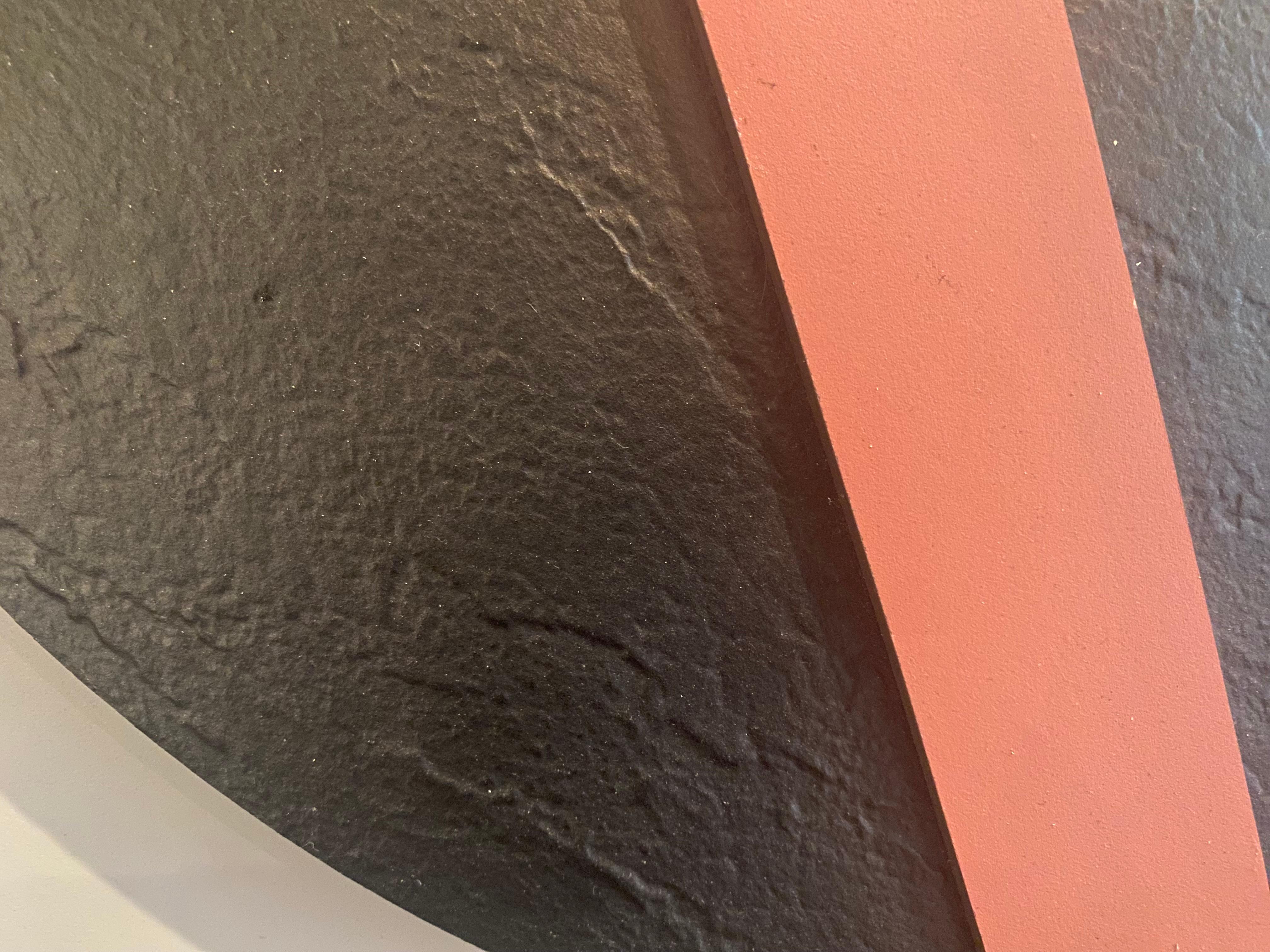 This wall sculpture is based on an assembly of cut and superimposed geometric shapes. The colors – anthracite, gray, pink, and purple– are applied in flat, even tones without gradients, reinforcing the rigor of the composition. Each hue defines a