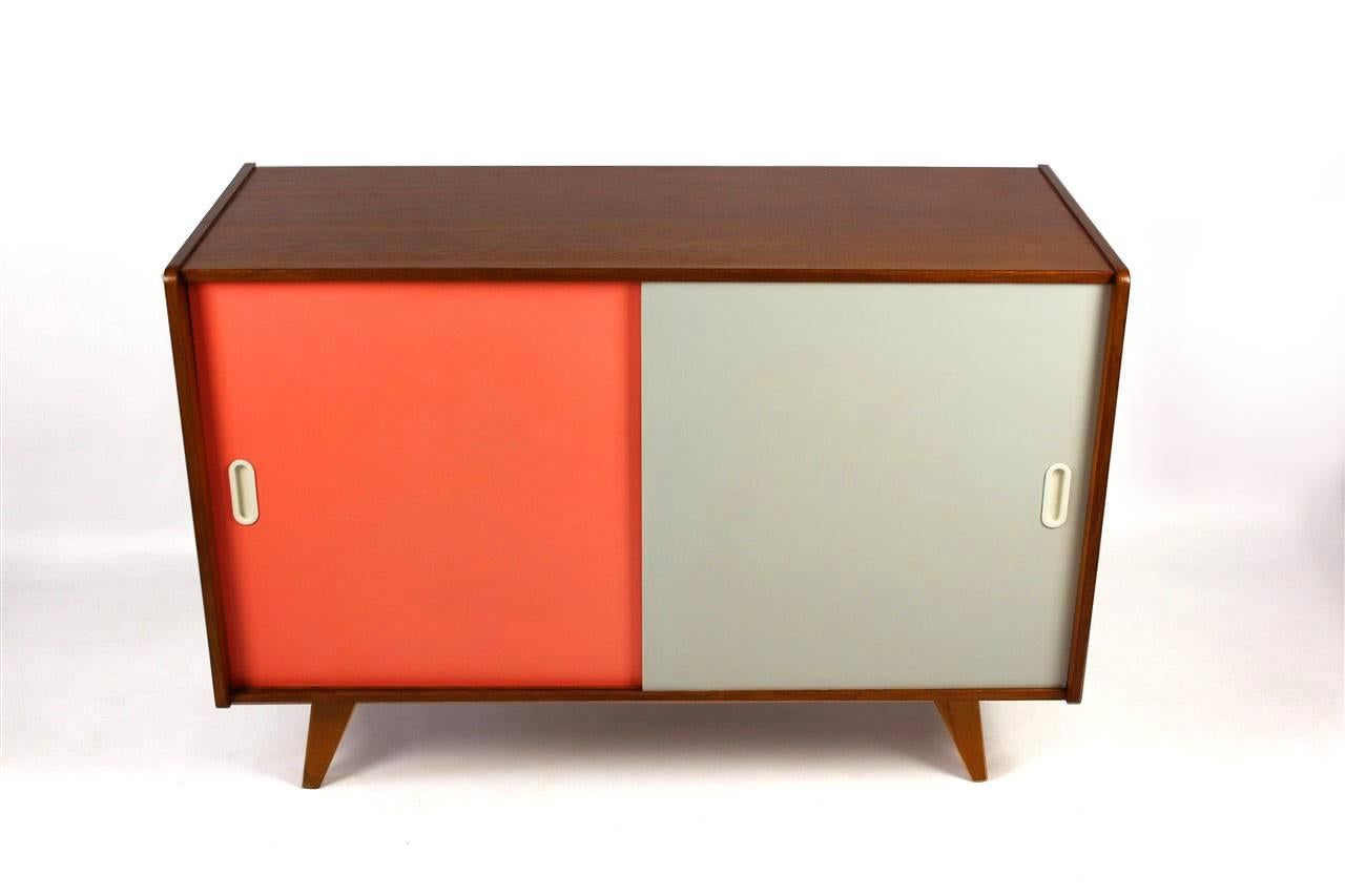 This midcentury wooden sideboard with slide doors was designed by Jirí Jiroutek for Interiér Praha in the 1960s.
Features one long shelf inside and original pink and grey formica fronts. Woodwork has been completely restored, finished in a satin