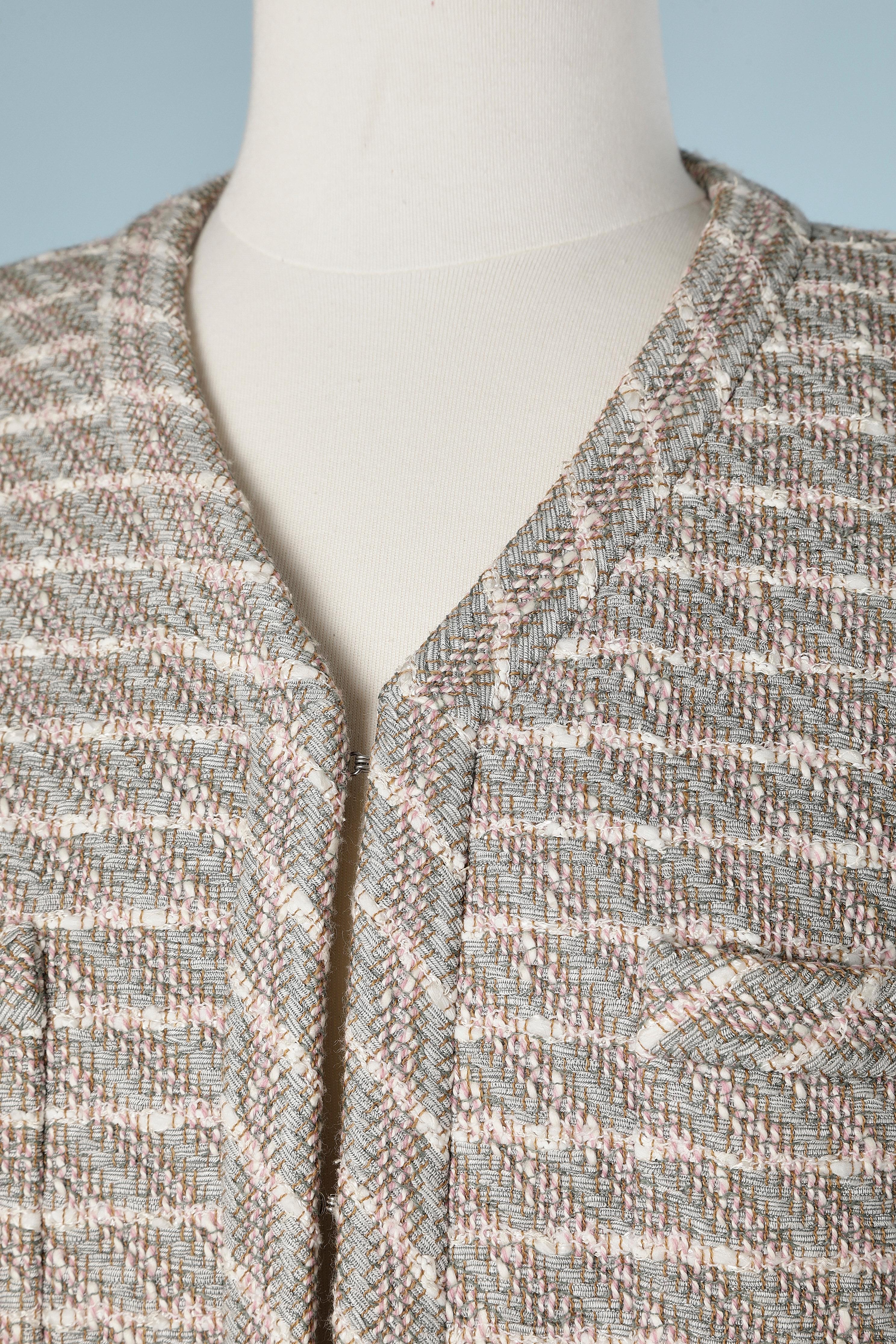 Pink and grey tweed edge to edge jacket with striped silk lining.
Metallic chain in the inside edge of the jacket. Small shoulder pad. 
Hook&eye to close the jacket in the middle front. Branded mother of pearl buttons and buttonhole at the end of