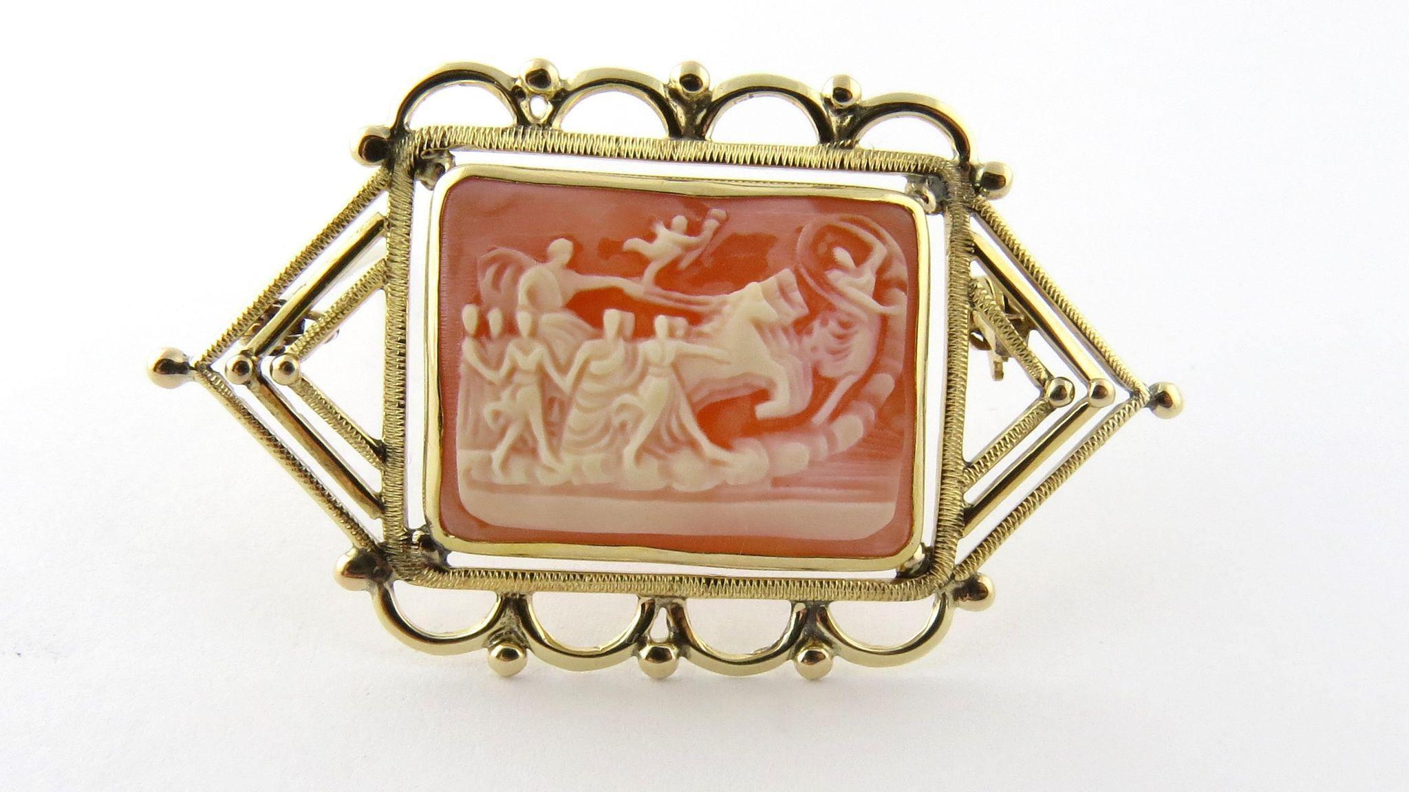Artfully designed handmade 14K yellow gold frame brooch houses a skillfully carved cameo depicting a chariot scene. 

Vintage Cameo scene depicts a chariot with driver and three horses. Dancers to the side and front of the chariot and an