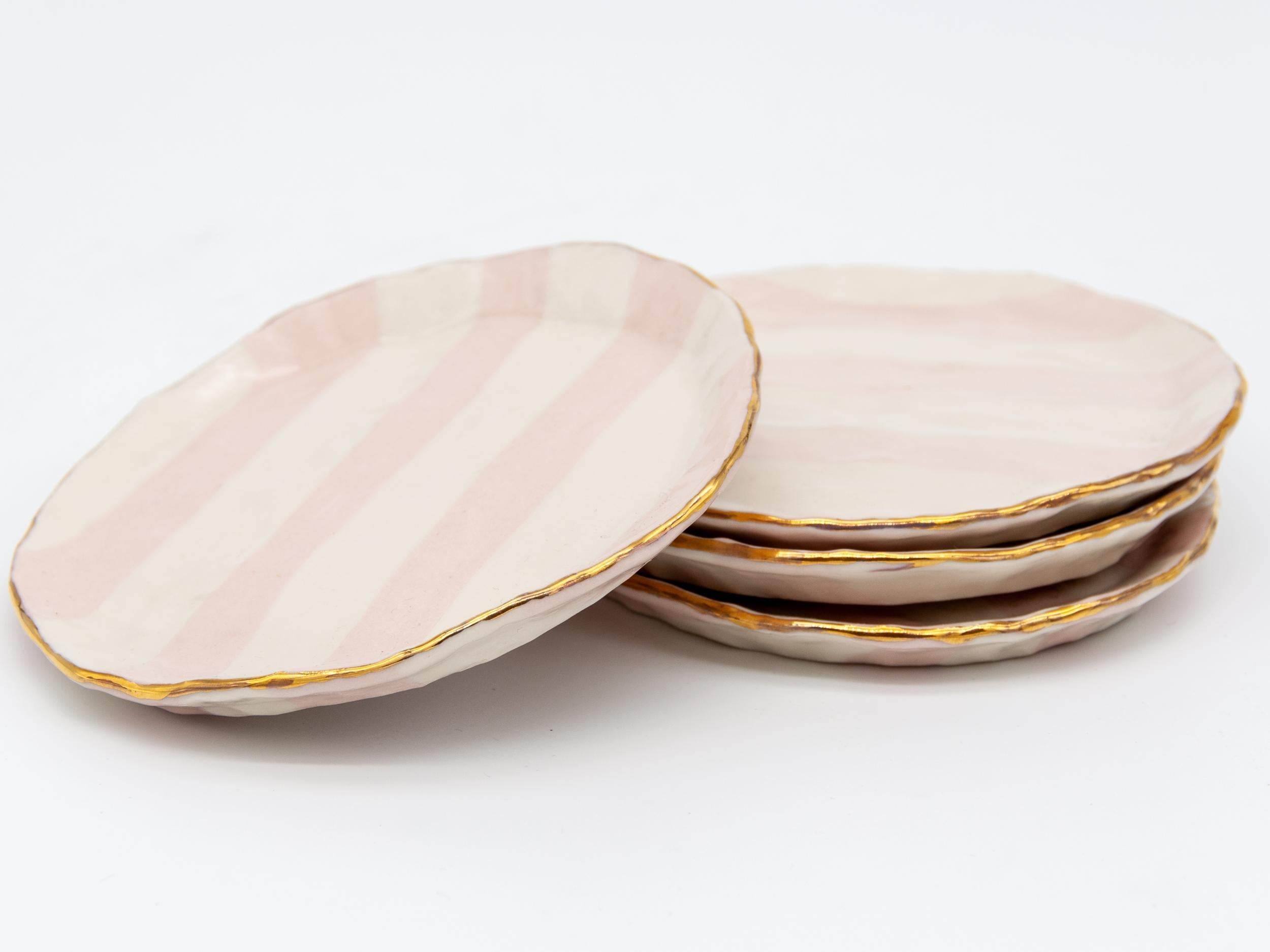 Isabel Halley is a 21st-century ceramic artist based in Brooklyn, NY. She handcrafts all her designs making this set of pink and ivory Ribbon Plates with gold trim.