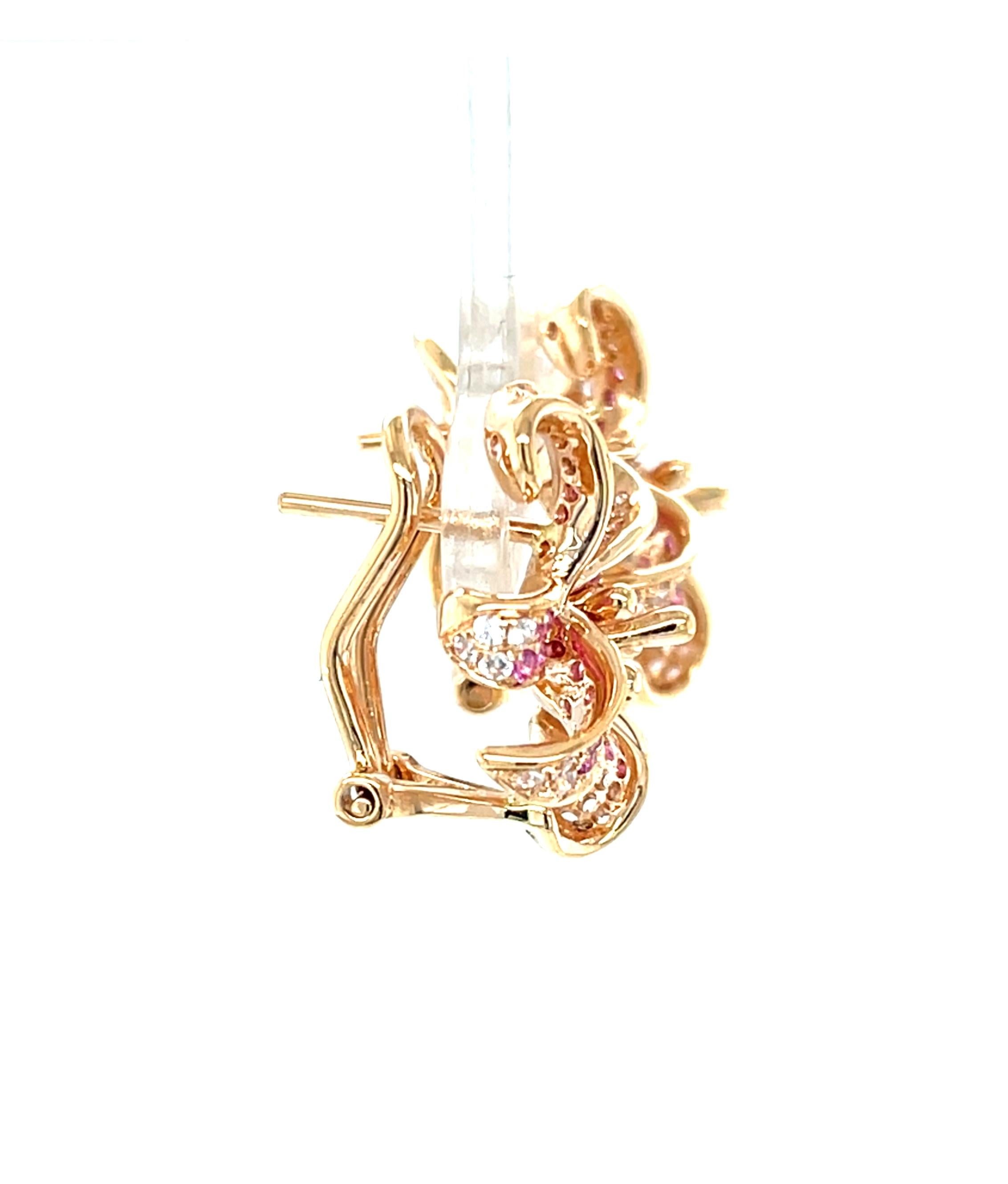 Questi bellissimi orecchini in oro rosa 18 carati presentano una splendida combinazione di zaffiri bianchi e rosa scintillanti, incastonati in un grazioso giglio rubro. I colori vivaci imitano il ricco contrasto cremisi/bianco di questi fiori