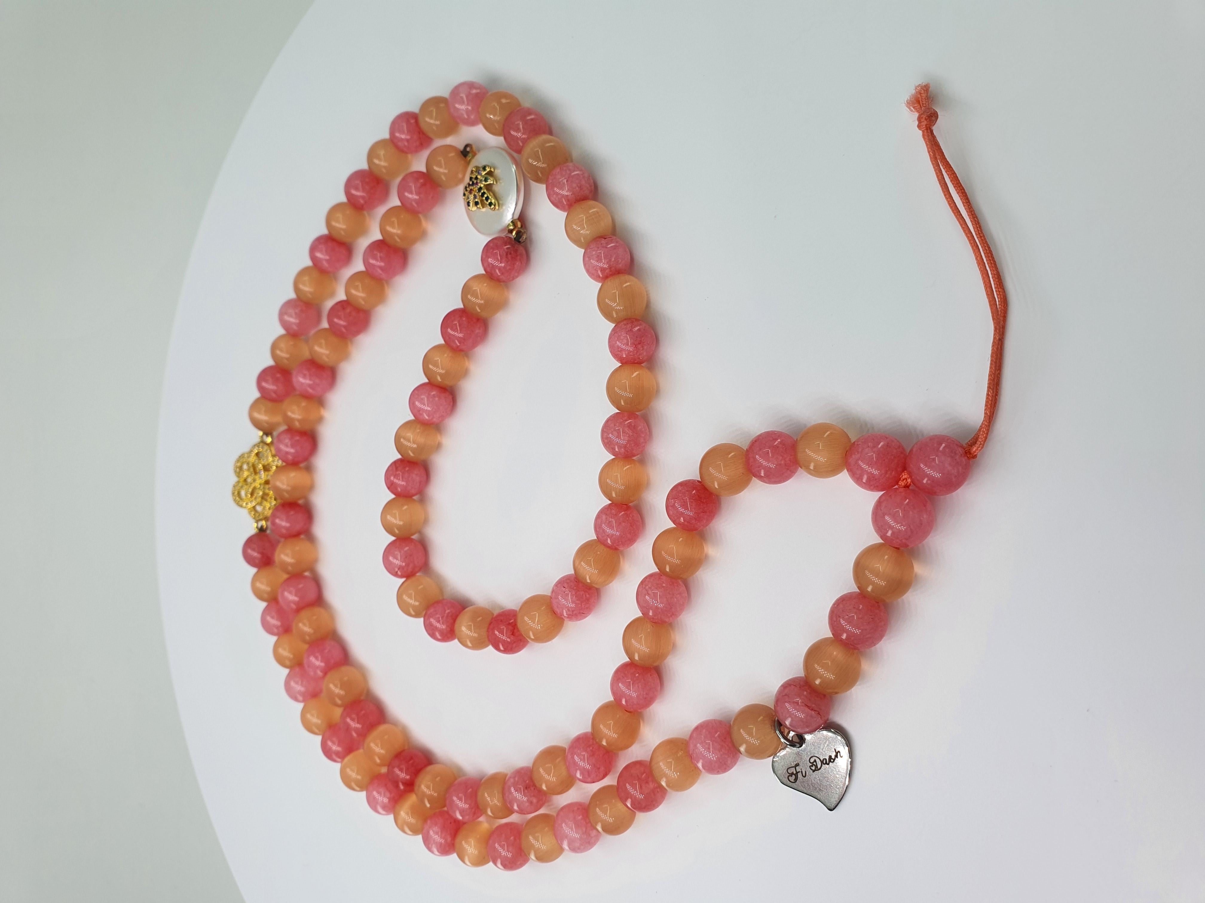 This beautiful fashion pink angelite and peach cat eye beads strap with 2 charms: multicolor palm and  golden swirl can be used as an accessory for a phone, as necklace or a handbag accessory. This strap is carefully handcrafted by our artisans.