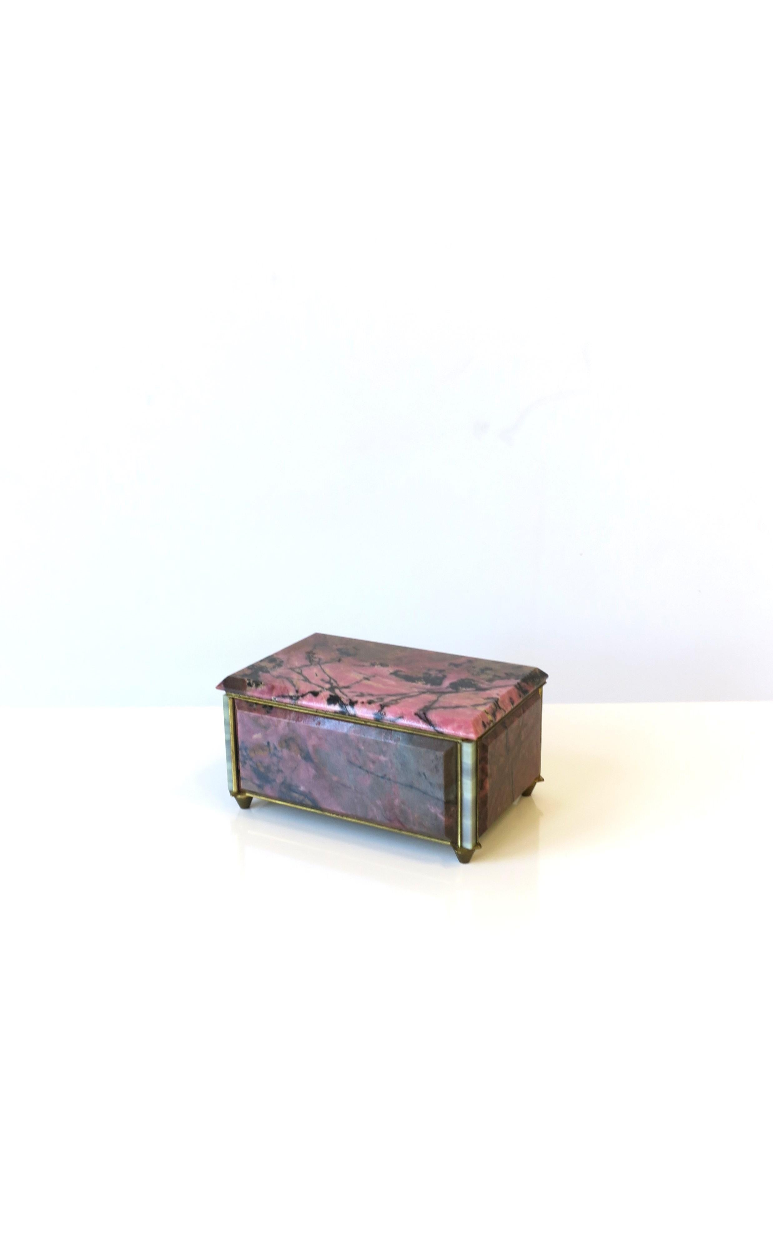 A very beautiful and rare pink and black rhodonite quartz jewelry box with bronze frame and a midnight blue velvet interior, circa early-20th century, Europe. Box is pink and black rhodonite with white onyx corners, embraced by a bronze frame,