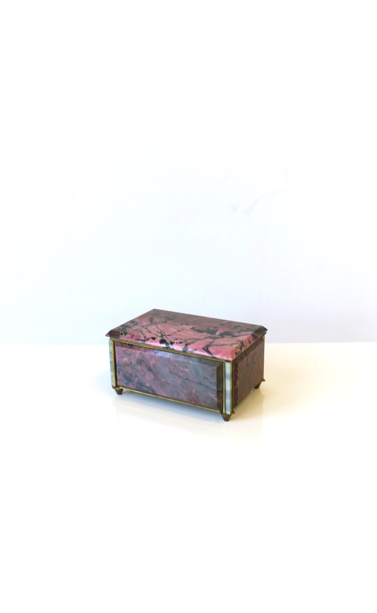 A very beautiful pink and black rhodonite stone jewelry box with bronze frame and a midnight blue velvet interior, circa early-20th century, Europe. Box is pink and black rhodonite stone with white onyx corners, embraced by a bronze frame, finished