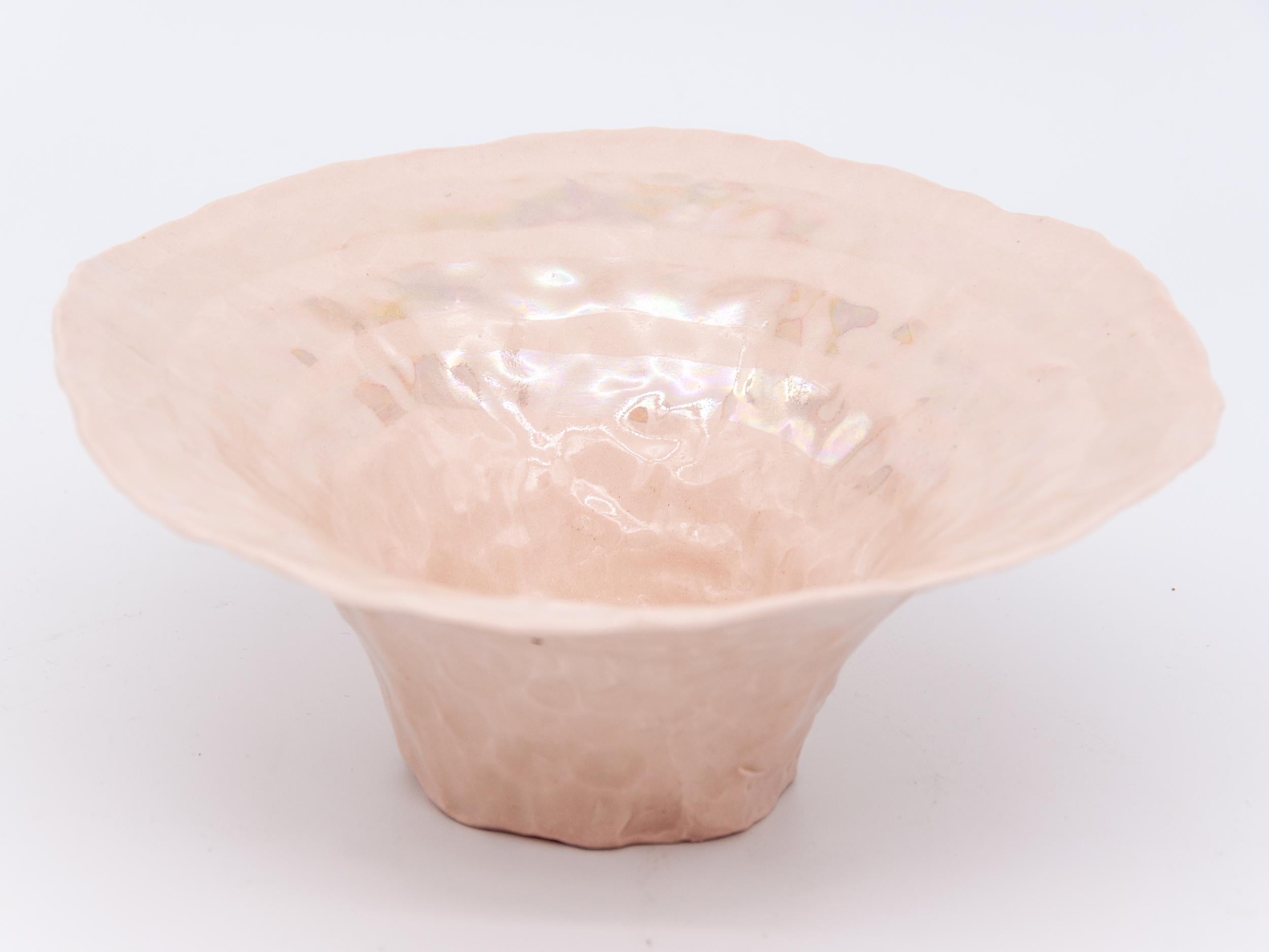 Isabel Halley is a 21st-century ceramic artist based in Brooklyn, NY. She handcrafts all her designs making this pink pinch bowl with stripes in a pearl luster.