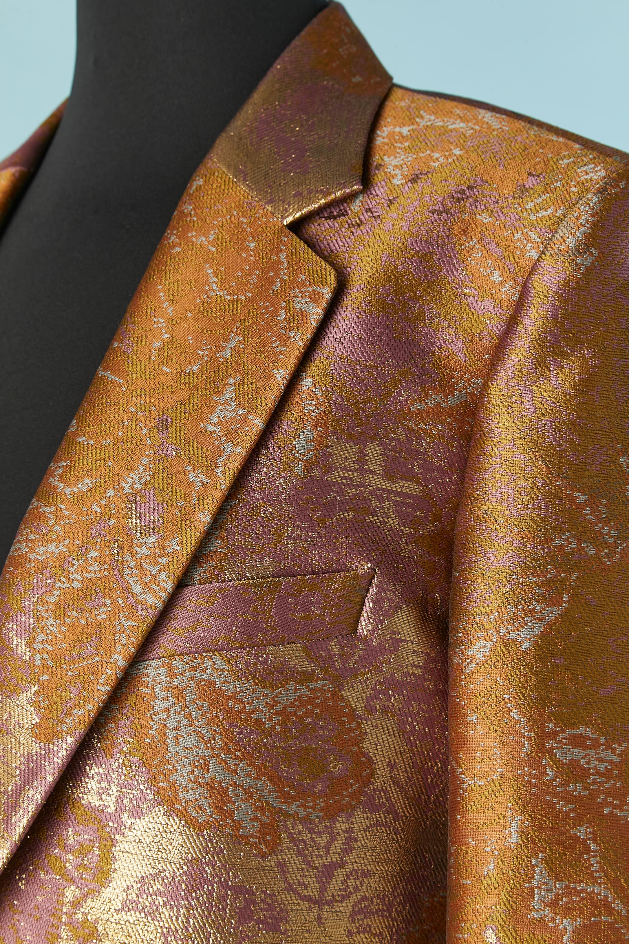 Einreihige Jacke aus rosa, braunem und goldenem Jacquard. Zusammensetzung des Obermaterials: 92% Polyester, 8% Nylon. Zusammensetzung des Futters: 100% Viskose. 
Schulterpolster. Knopf- und Knopflochverschluss in der vorderen Mitte und an den