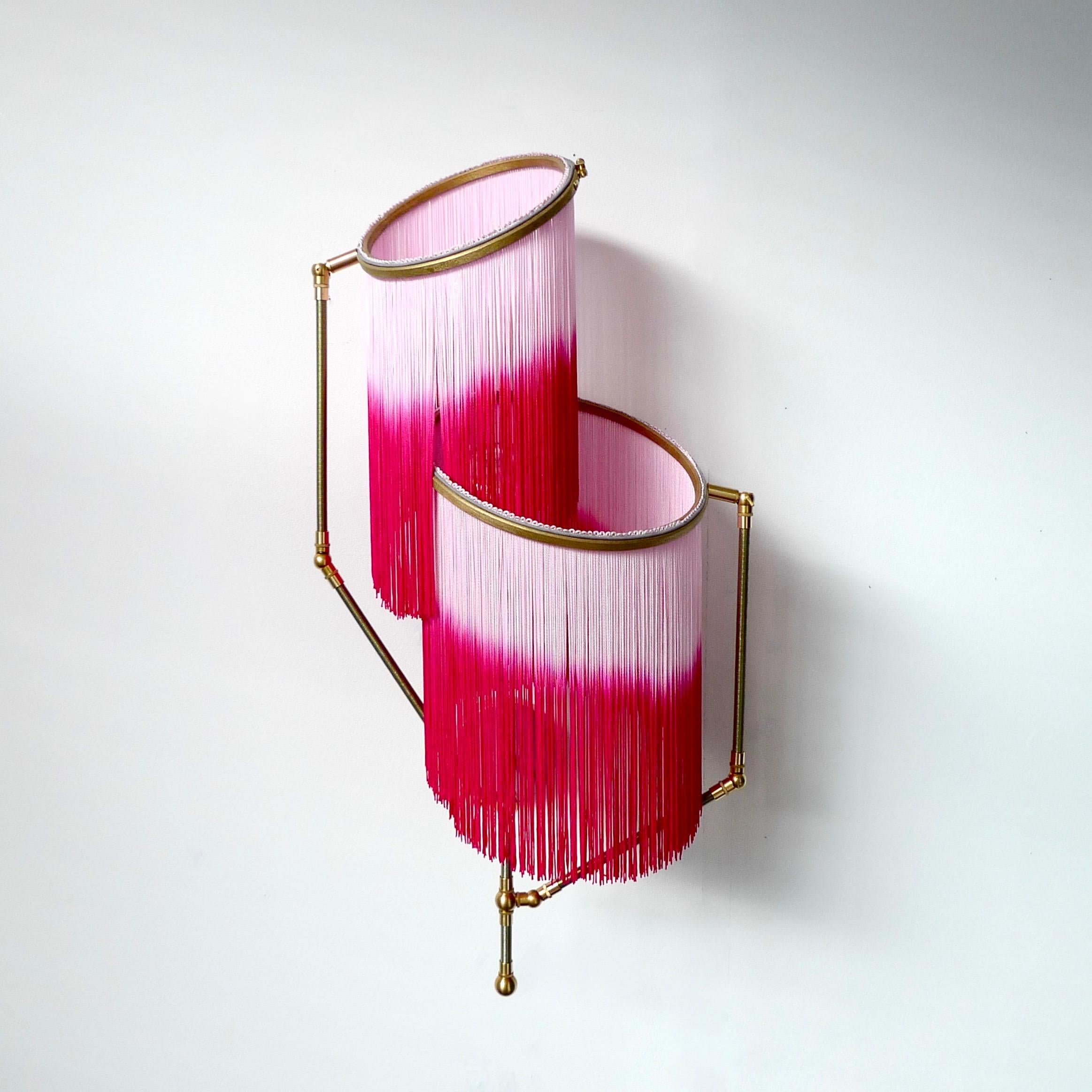 Pink charmed sconce lamp, Sander Bottinga

Dimensions: 50 x W 38 x D 27 cm
Handmade in brass, leather, wood and dip dyed colored Fringes in viscose.
The movable arms makes it possible to move the circles with fringes in different positions.
So
