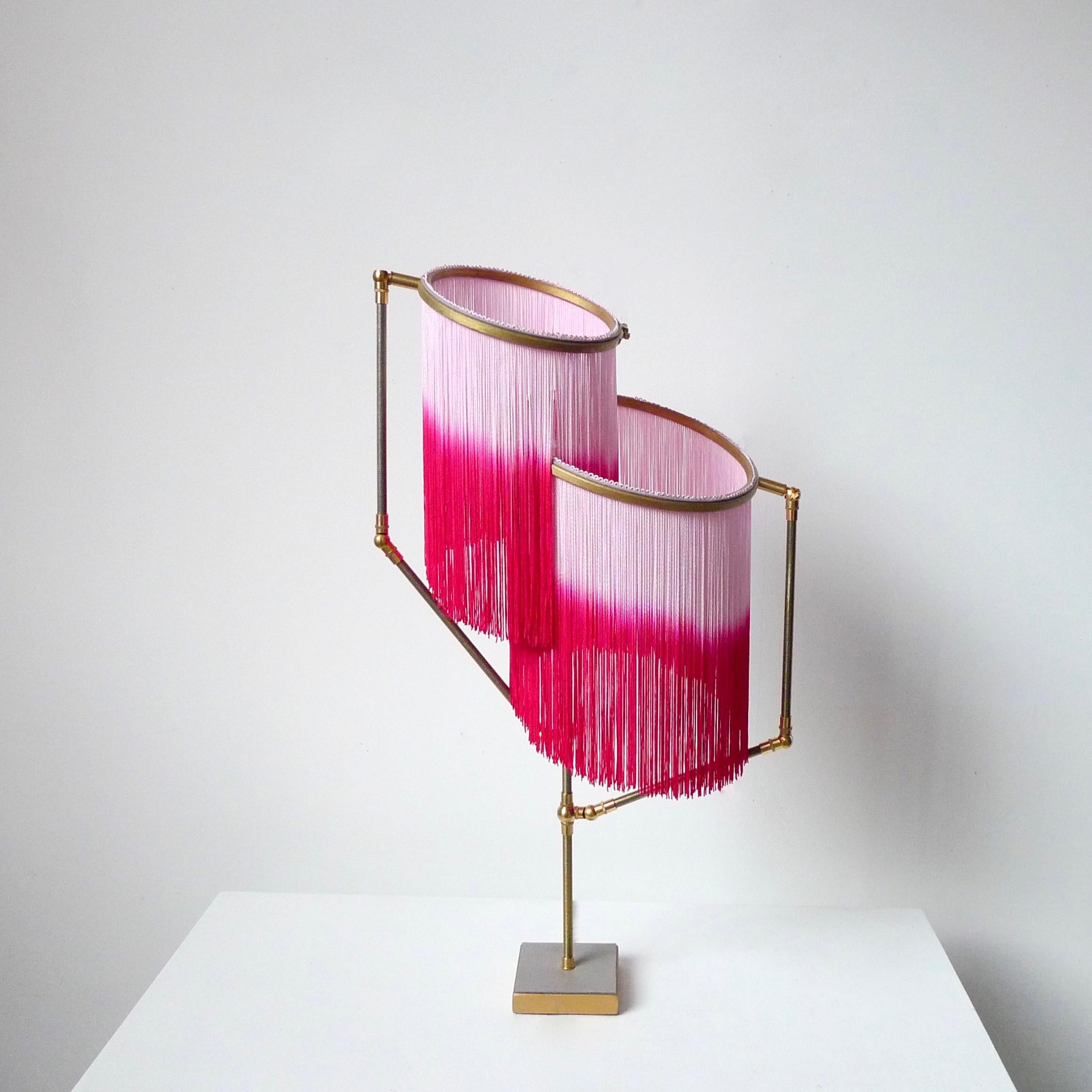 Pink charme table lamp, Sander Bottinga

Dimensions: H 73 x W 38 x D 25 cm
Handmade in brass, leather, wood and dip dyed colored Fringes in viscose.
The movable arms makes it possible to move the circles with fringes in different positions.
So