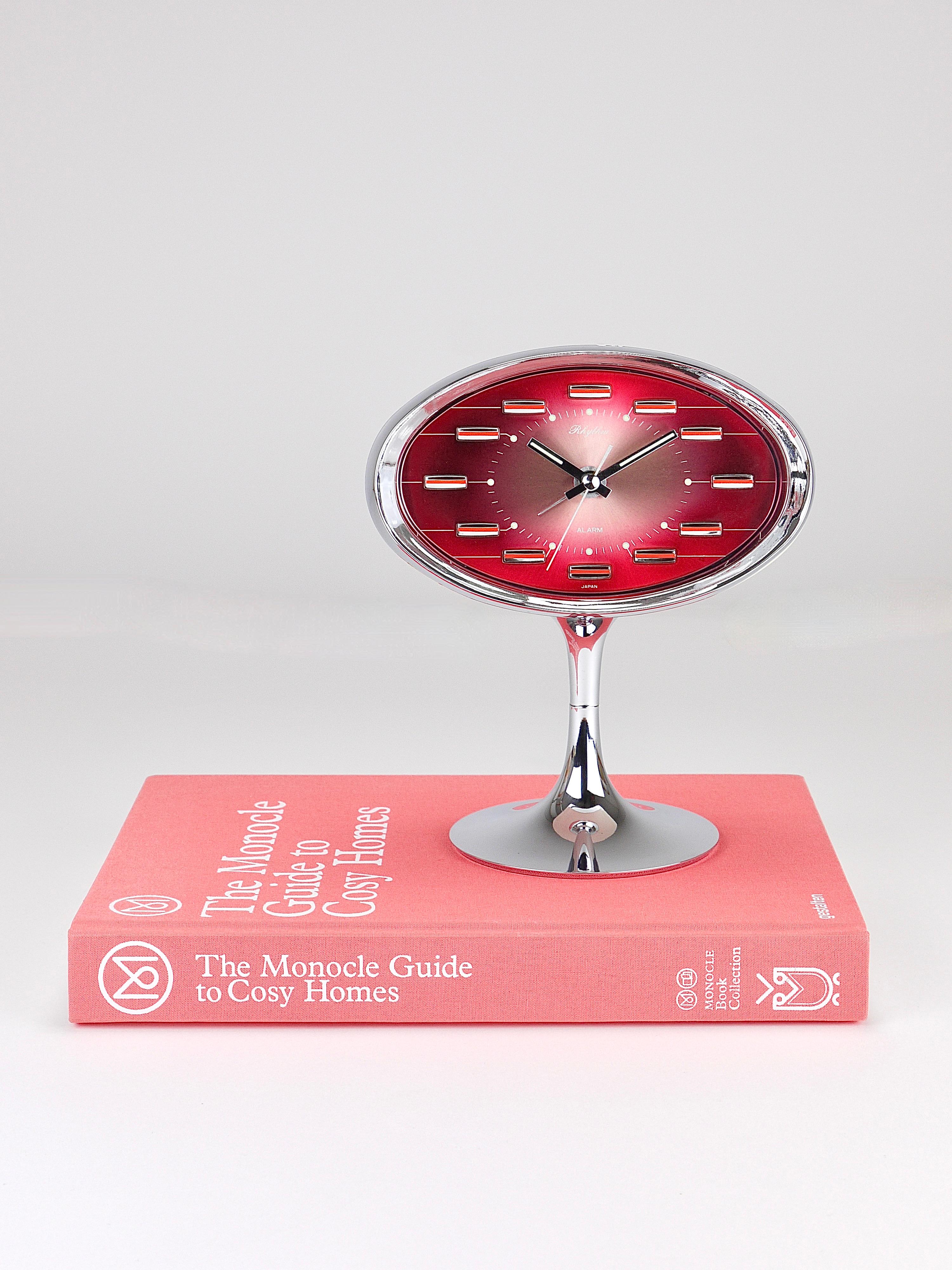 A stylish Space Age desk or table alarm clock from the 1970s, made by Rhythm — a Japanese company renowned for producing beautiful clocks since the 1950s. In our opinion, this is their best model, featuring an oval case on a fully chromed tulip base