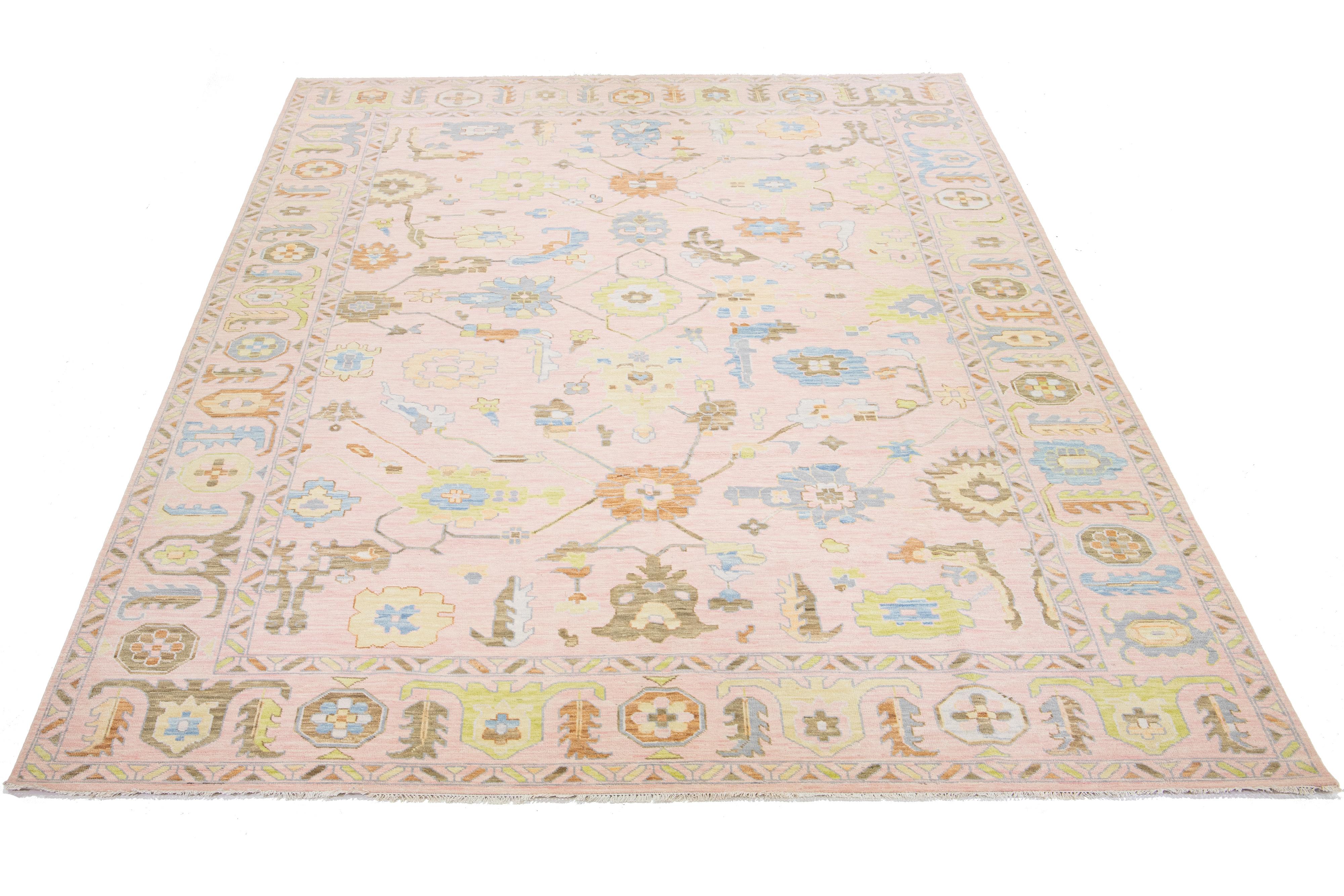 This Oushak-style rug features a hand-knotted pink field. It embodies a mid-century modern style with an all-over multicolored floral design.

This rug measures 12'2