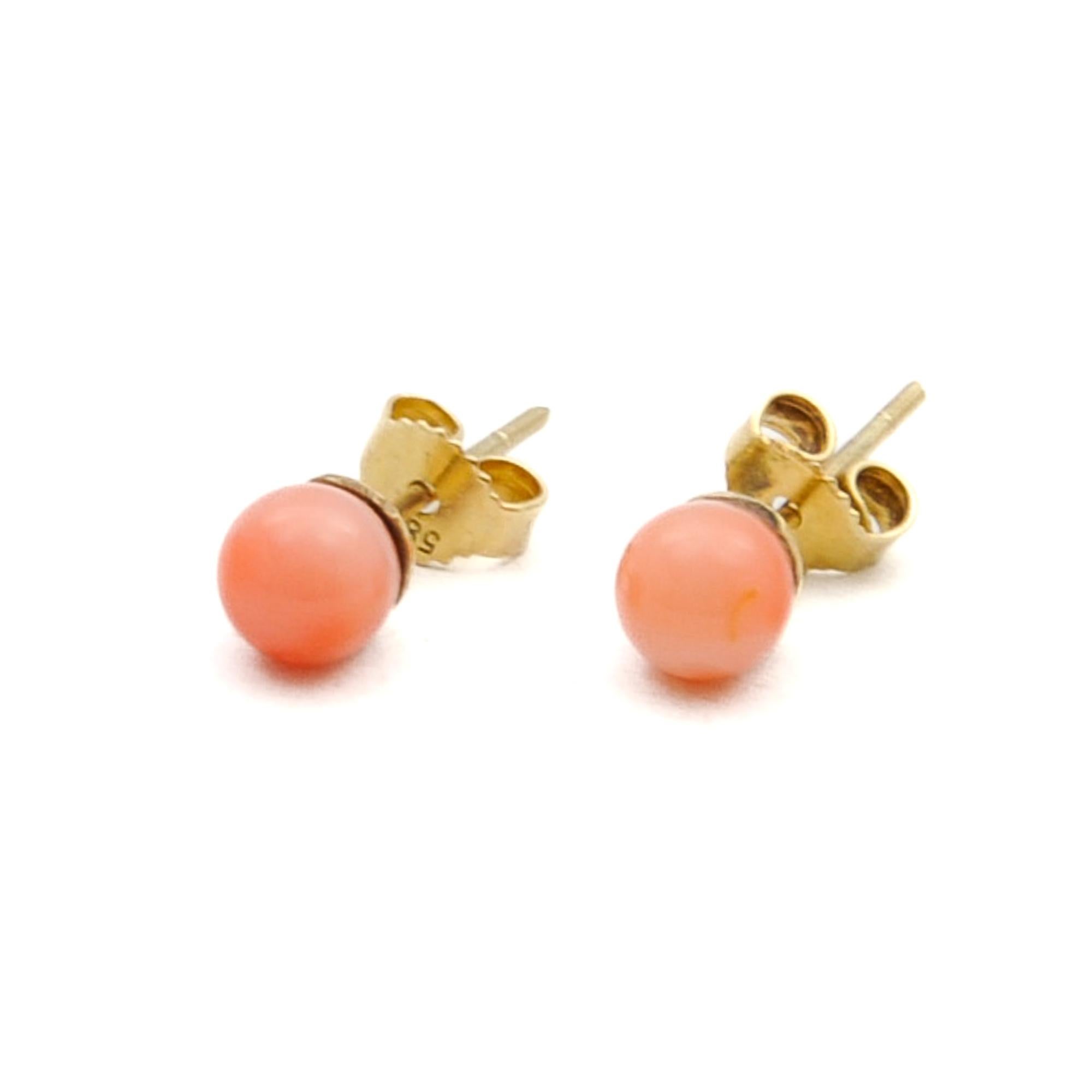 These lovely pink coral stud earrings are set in a 14 karat gold frame. The coral of these beautiful colored studs are round shaped and mottled with different hues of red pink. Coral is considered a symbol of renewal, vitality and beauty. The studs