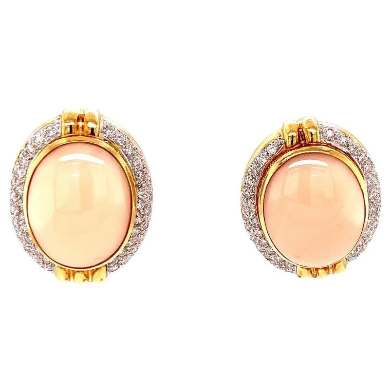 One pair of angelskin pink coral and diamond 18K yellow gold earrings featuring two oval cabochons pink coral portions measuring 20 x 15 millimeters. Enhanced by 84 round brilliant diamonds totaling 1 ct. Circa 1960s.

Pristine, pretty,