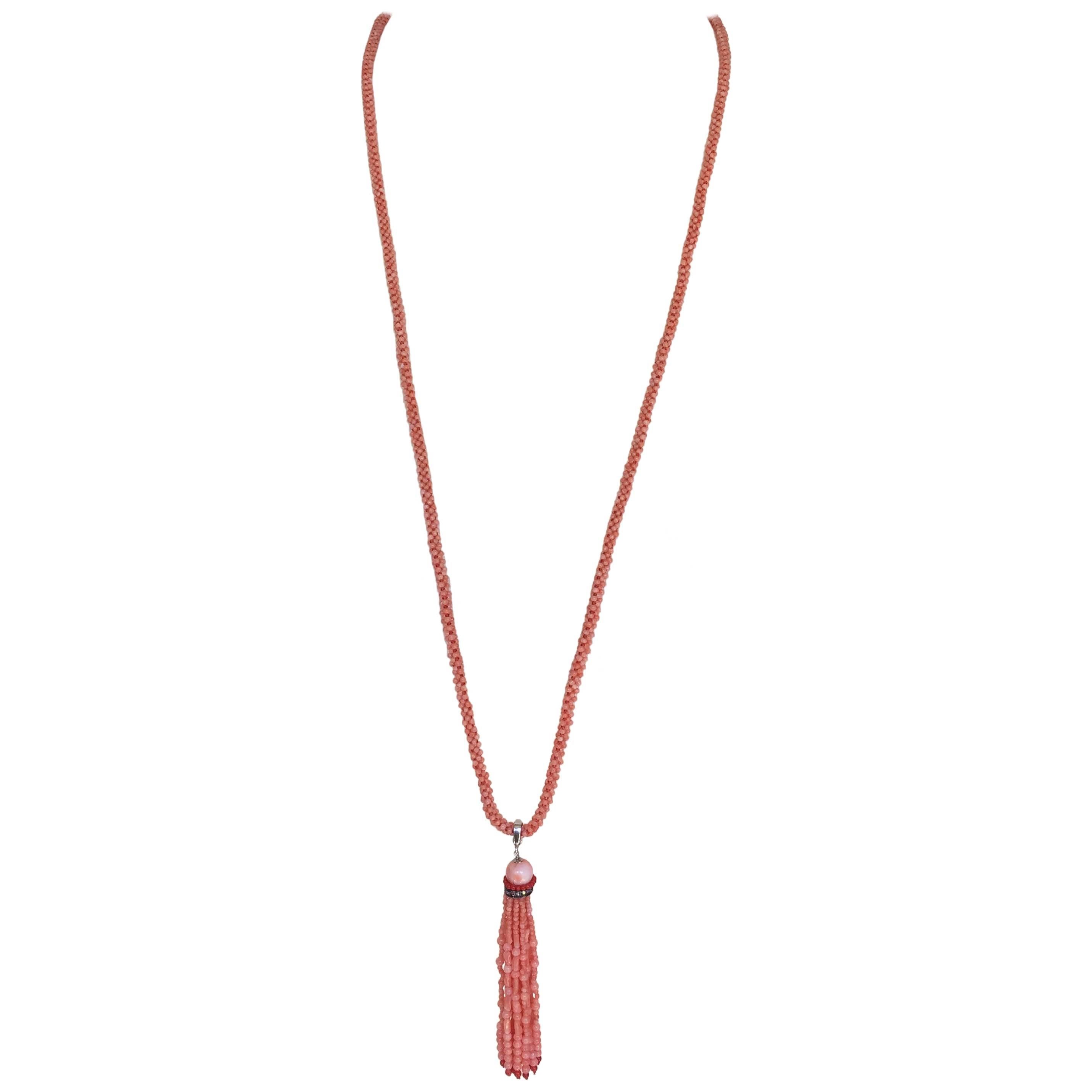 This pink coral cord necklace gracefully hangs with a coral tassel. The tassel has a round rose pink bead atop rich red coral beads and a diamond encrusted roundel. The strands are composed of graduated corals beads, with a mix of round and oblong