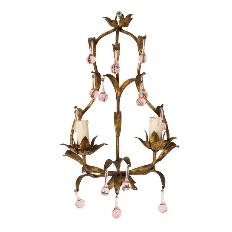Elegant pair of gilded wall sconces with pink crystal drops, from France circa early 20th century. Gleaming gilded foliage frame is decorated with pink-hued teardrop crystals. These light fixtures have been rewired for modern use, ready for