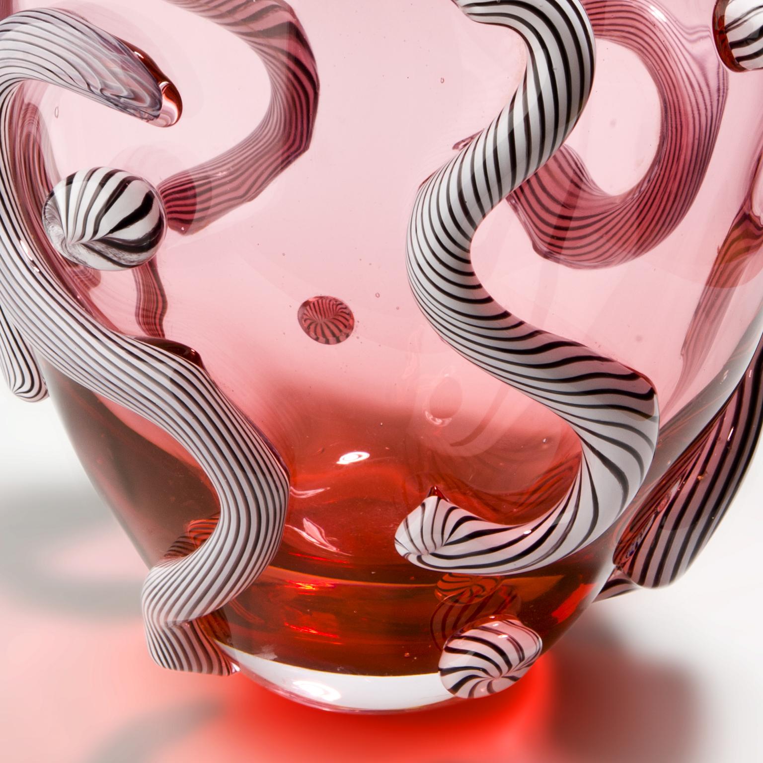 Pink hand blown glass object with black and white striped curls attached. Hand blown in Amsterdam.