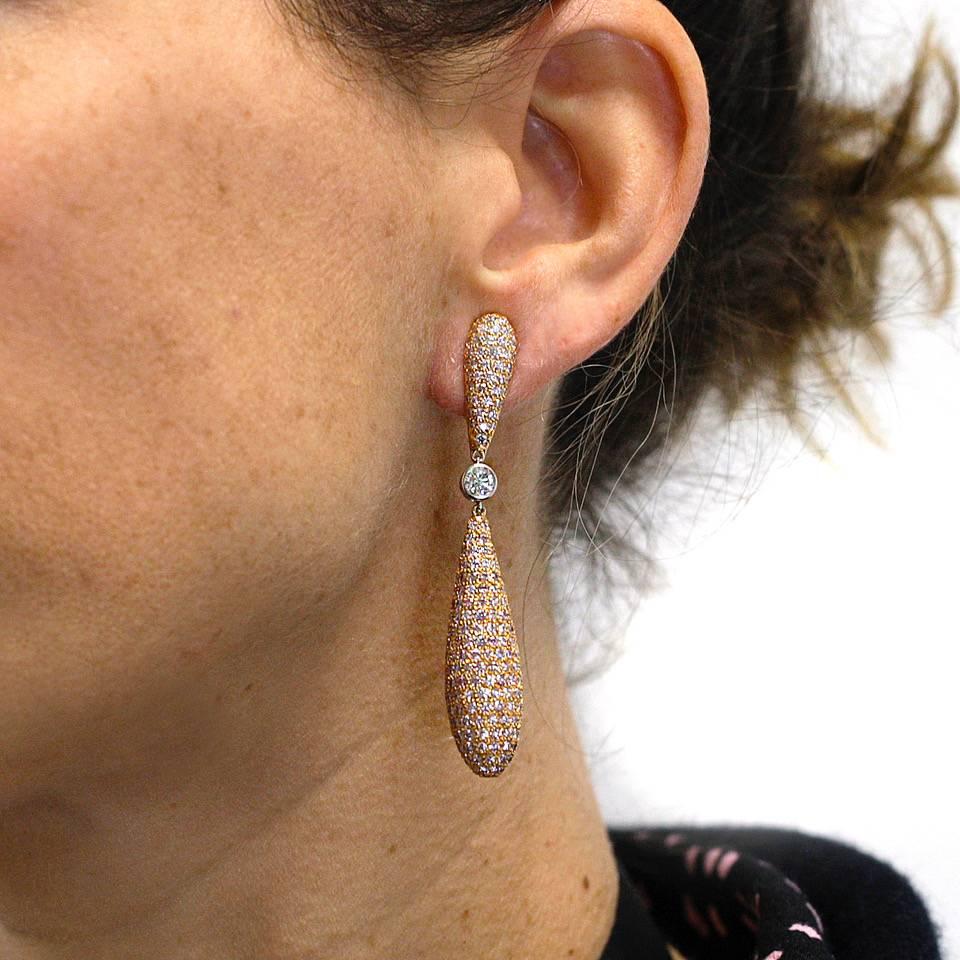 Eighteen karat pink gold and pink diamonds set in elongated teardrop earrings. The earrings are made up of 3 separate sections. The bottom is an elongated sphere made of eighteen karat rose gold that is encircled with pink diamonds which are pave