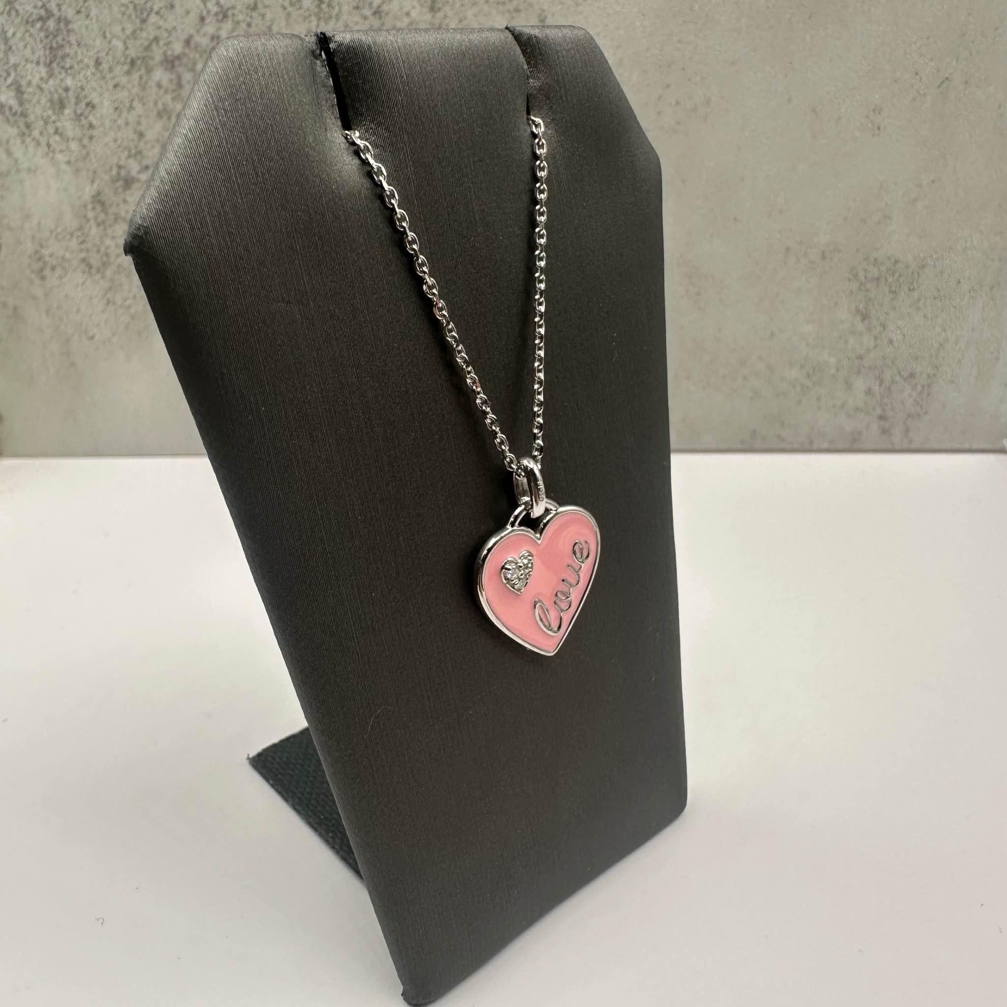 This charming Pink Enamel and Diamond Heart Necklace in sterling silver features 0.06ctw of natural GH SI round diamonds, adding a touch of sparkle to the playful pink enamel heart design. The necklace is adjustable from 17 to 20 inches, making it