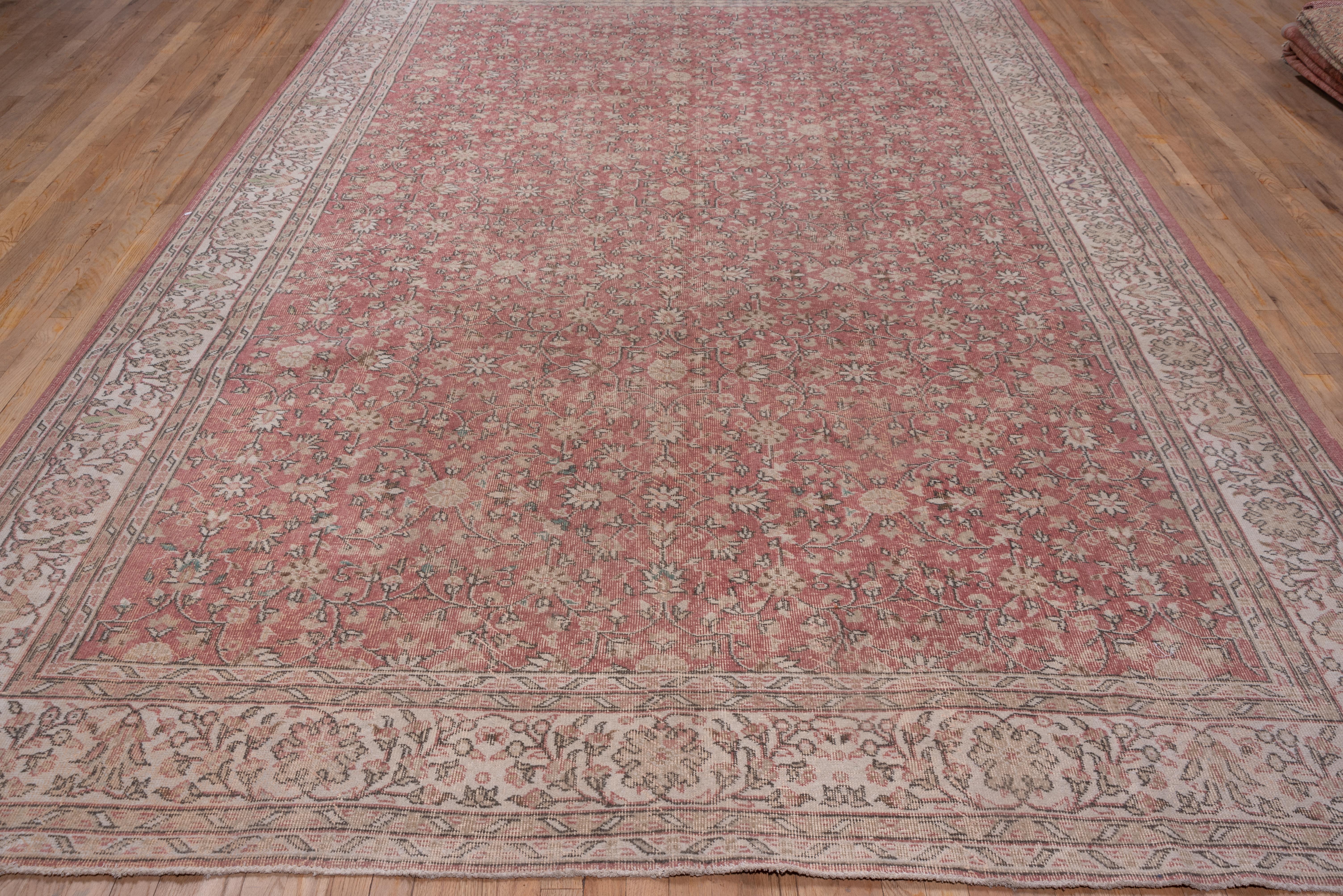 This Turkish town room size carpet has selective color corrosion. The taupe field displays rosette-centred octogrammes amidst curving, flowering stems, petal palmettes, a petal rosettes, detailed in cream, khaki, and dark brown. The cream main