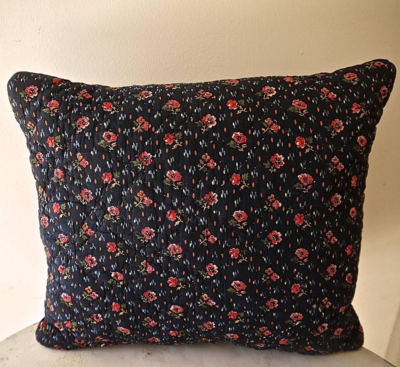 French, circa 1820s cotton block-printed and quilted cushion in a pretty design of pink red flowers heads and green leaves on an indigo ground. With paler blue, pink and white dashes of color. Backed in a natural hand-dyed natural indigo 19th