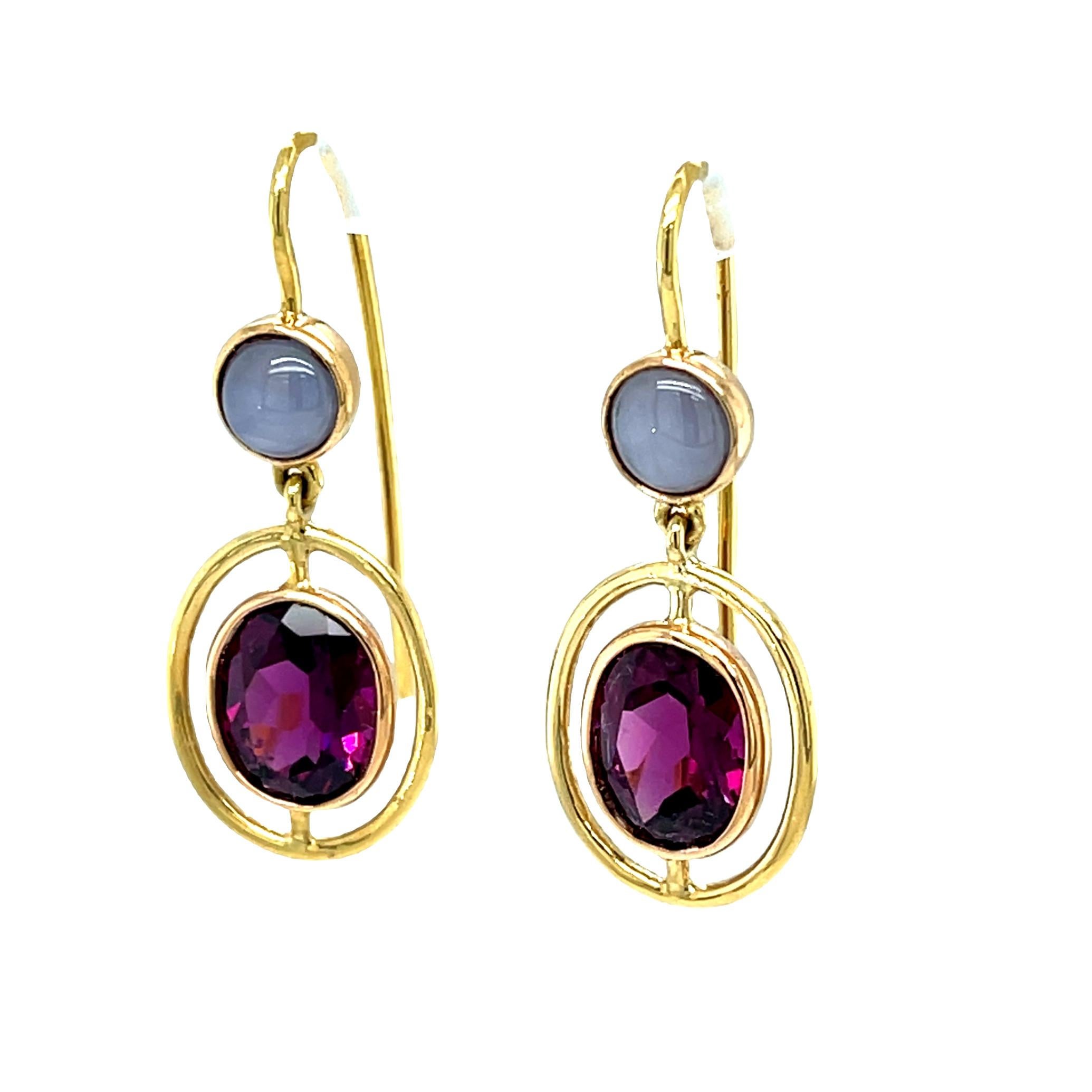 The unusual beauty of these one-of-a-kind earrings is undeniable! Richly colored rhodolite garnets are paired with silvery star sapphires to create an eye-catching combination of gemstones and visual effects. Pink gold bezels enhance the bright,